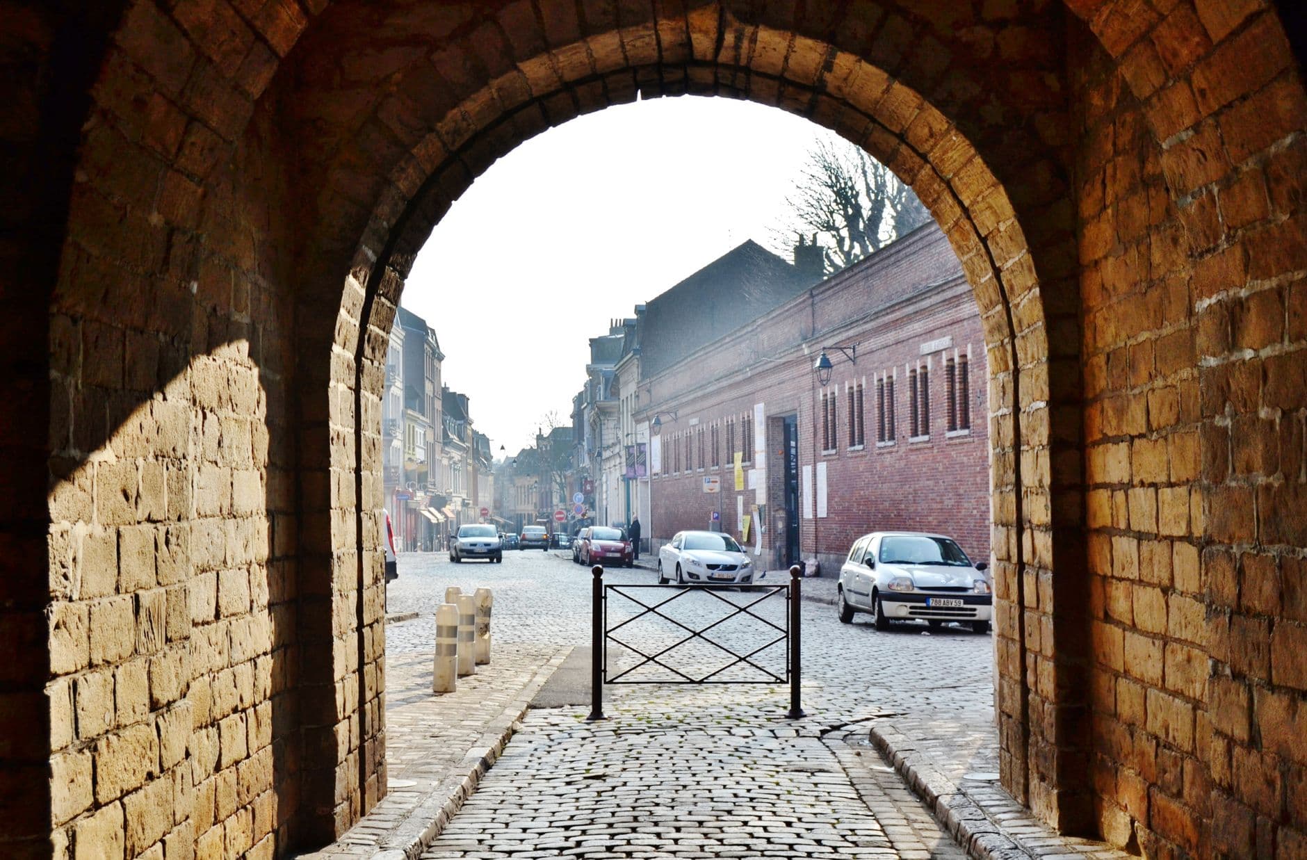 Captivating view through an ancient archway onto a narrow cobblestone street in Lille, France.