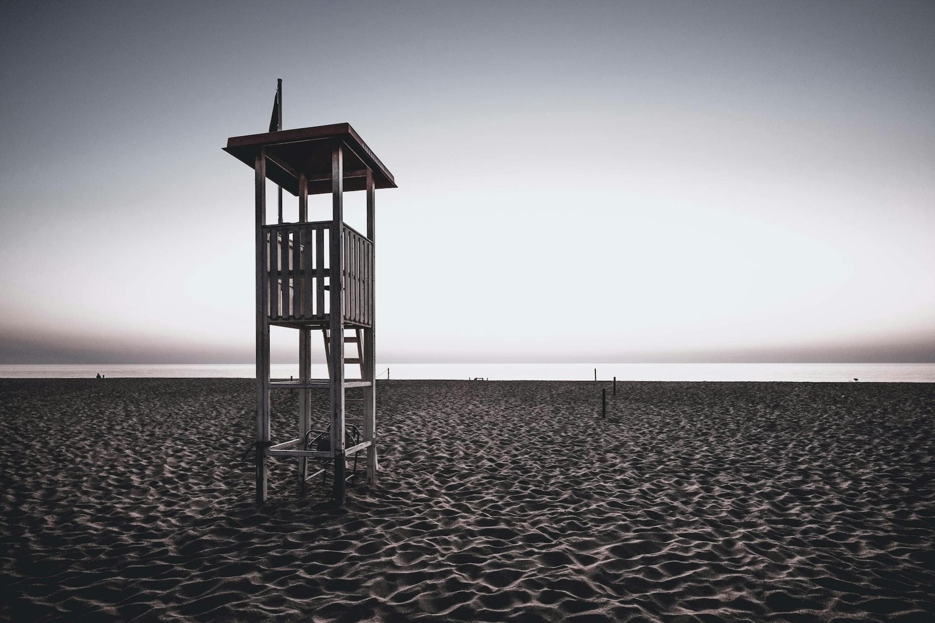 Lifeguard station located on empty wide sandy beach near endless ocean against cloudless sunset sky