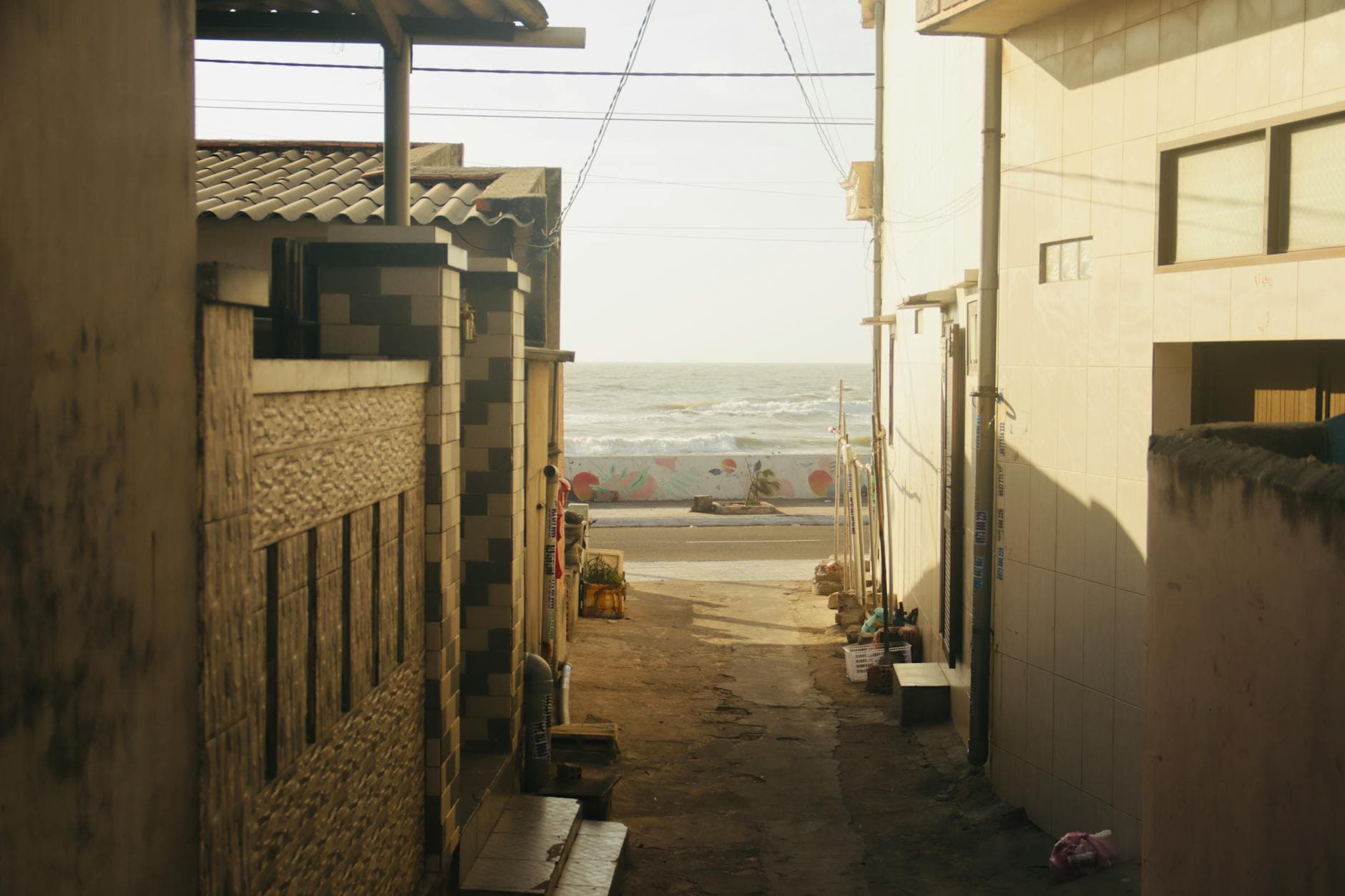 A picturesque alleyway opens to a scenic seaside view under summer sunlight.