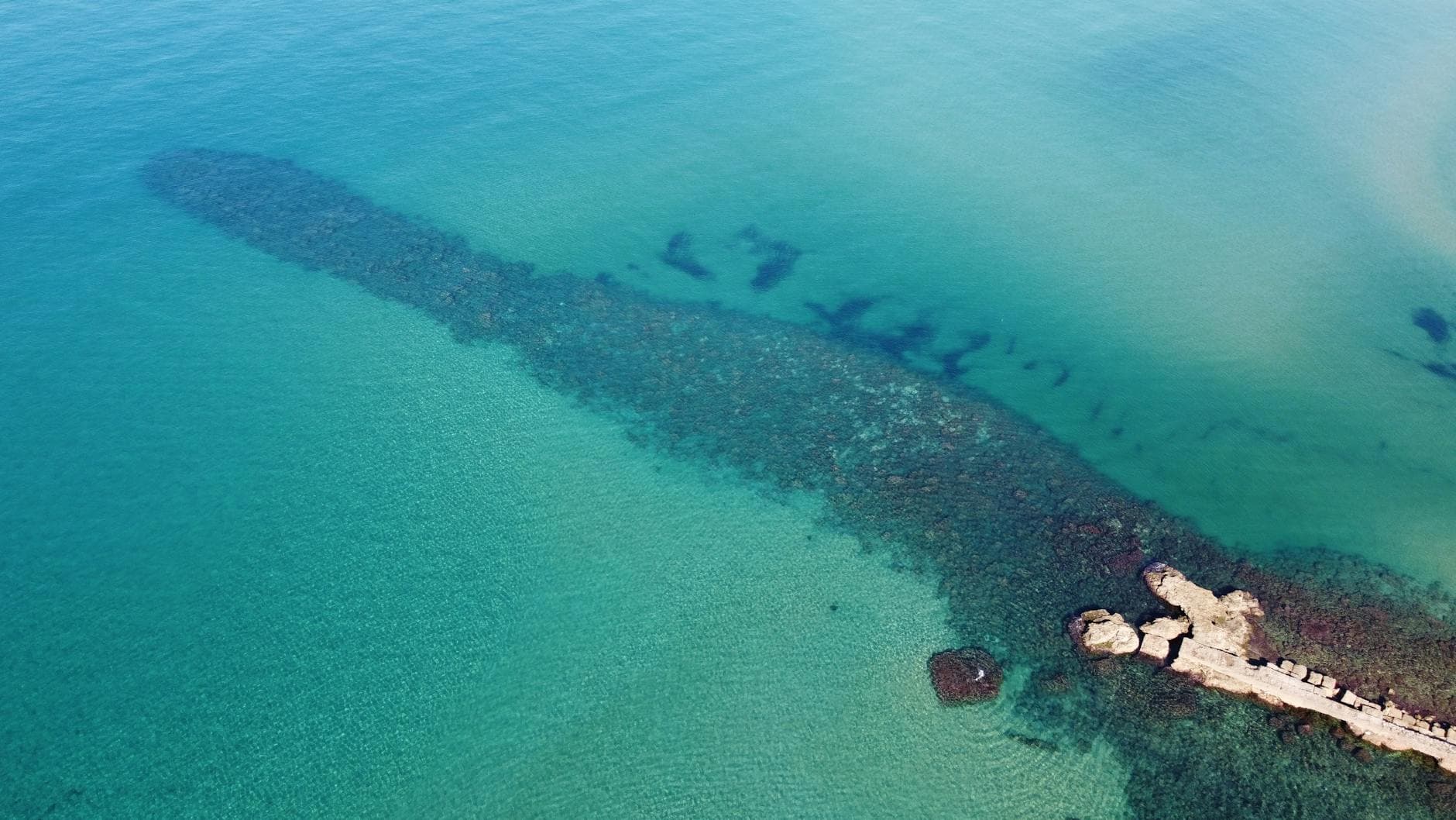 Stunning aerial view of Anzio's turquoise sea and rocky shoreline in Lazio, Italy.