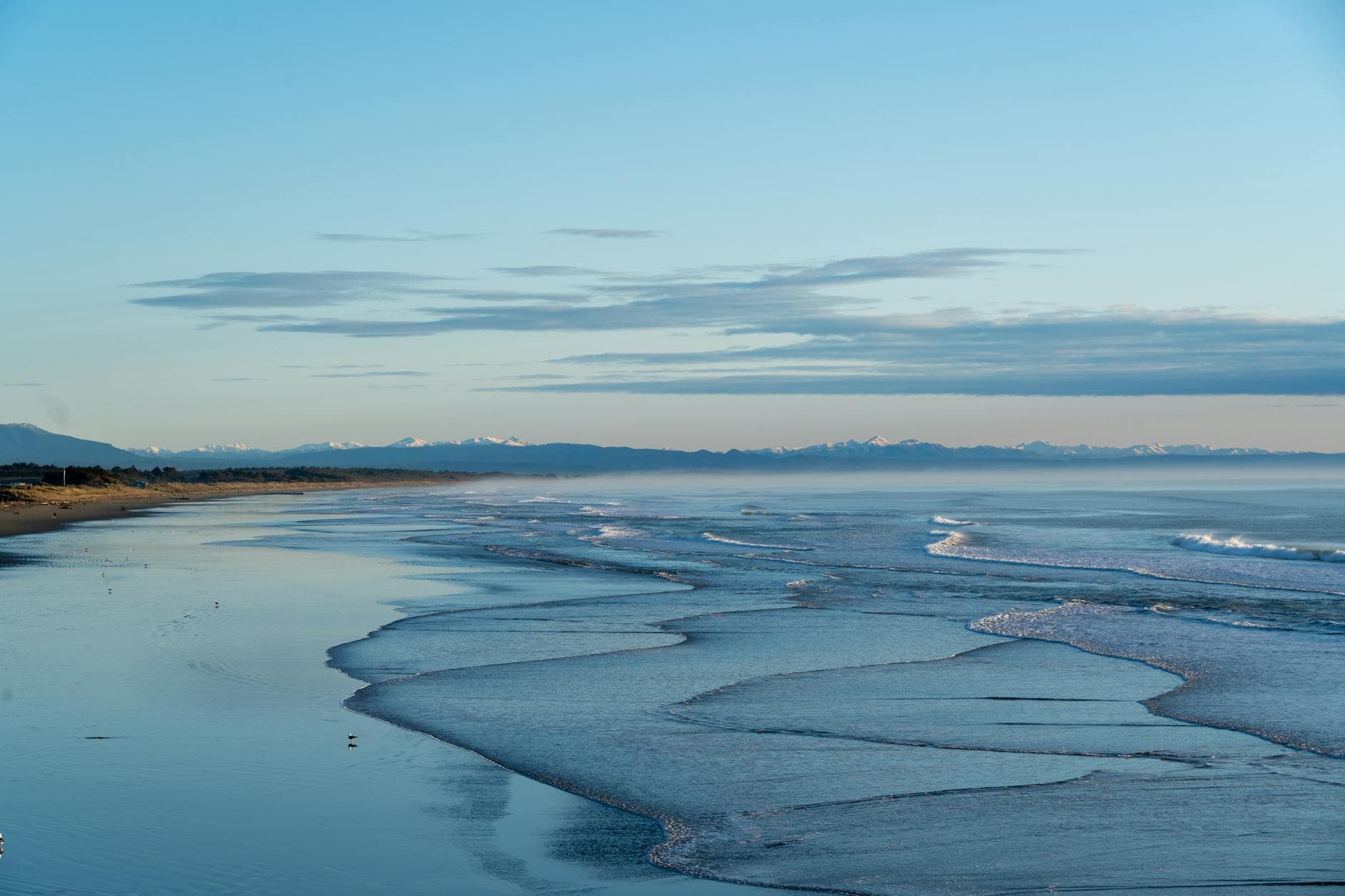 Elevated view of Christchurch coastline, capturing waves and serene sea under vast open sky.
