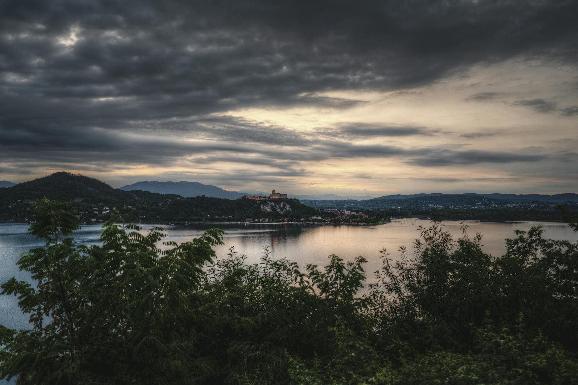 A stunning view of a fortress silhouetted against a dusk sky, reflecting on a serene lake.