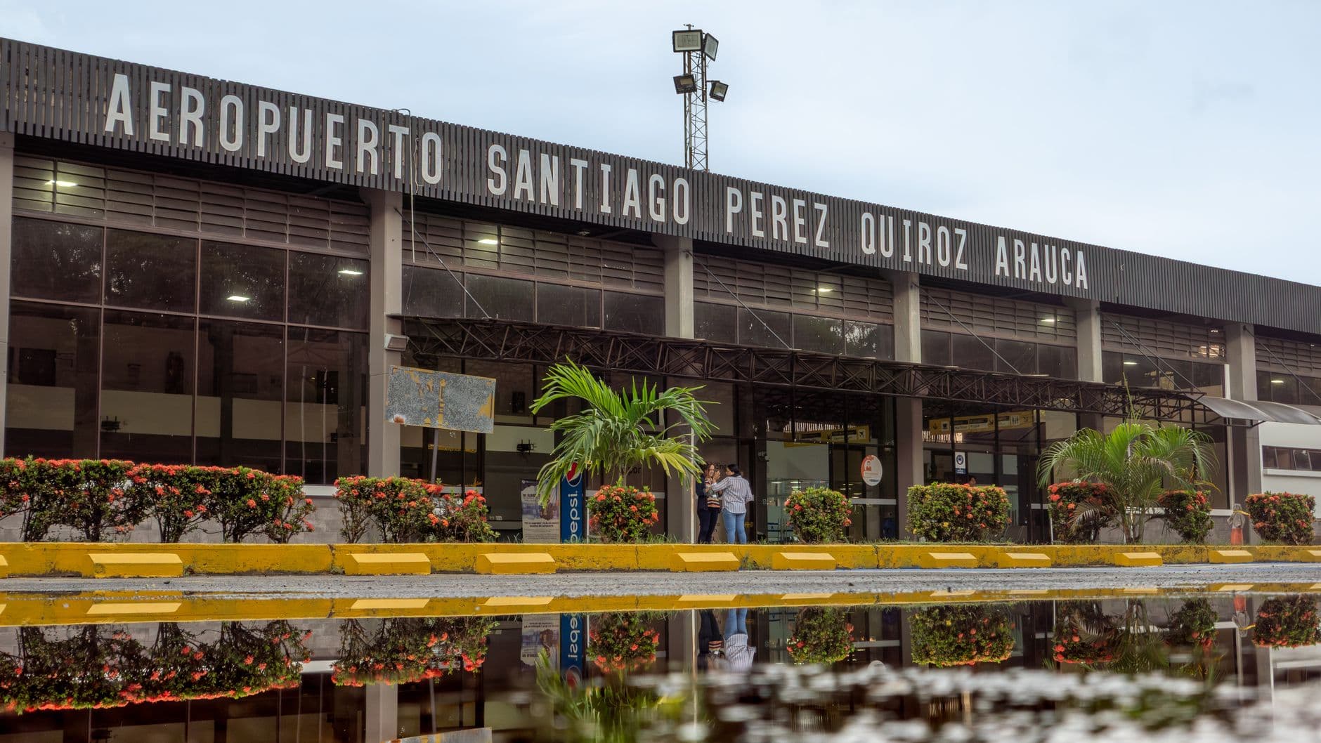 Exterior view of Santiago Perez Quiroz Airport in Arauca, Colombia, with reflection in a puddle.