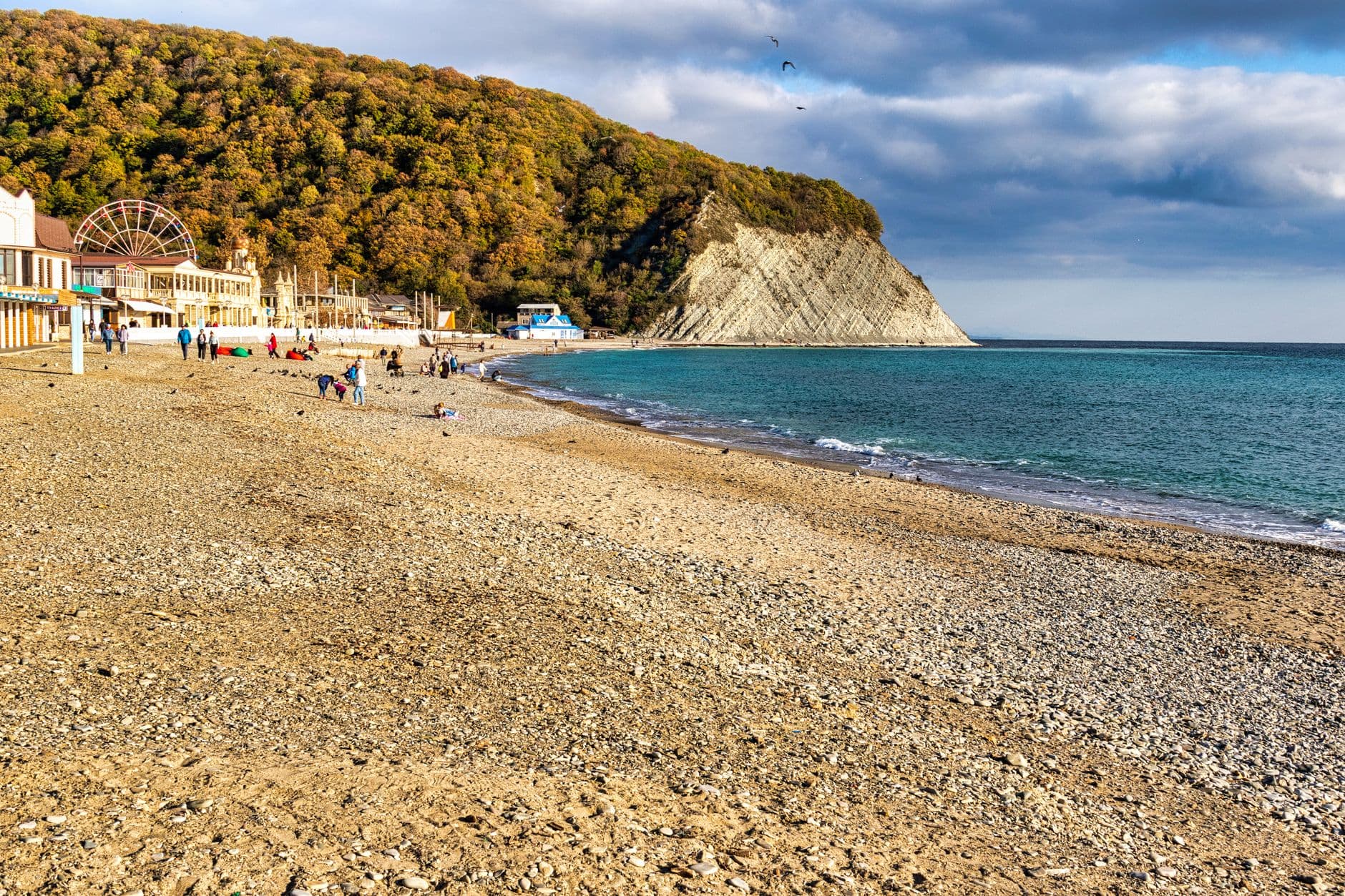 Sunny beach with people enjoying the coastline, vibrant seas, and scenic views.