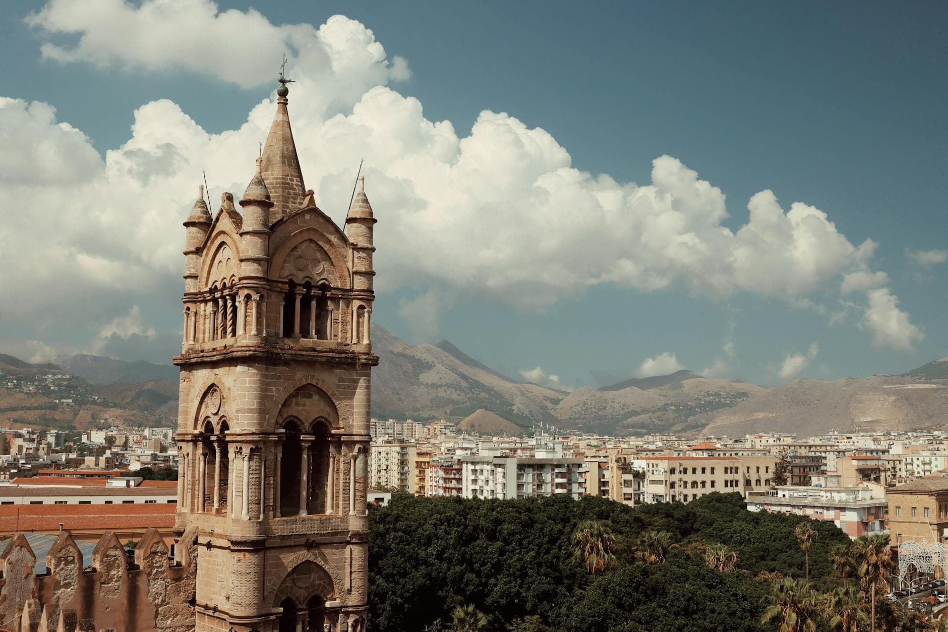 Medieval bell tower with cityscape of Palermo, Sicily under a bright blue sky.