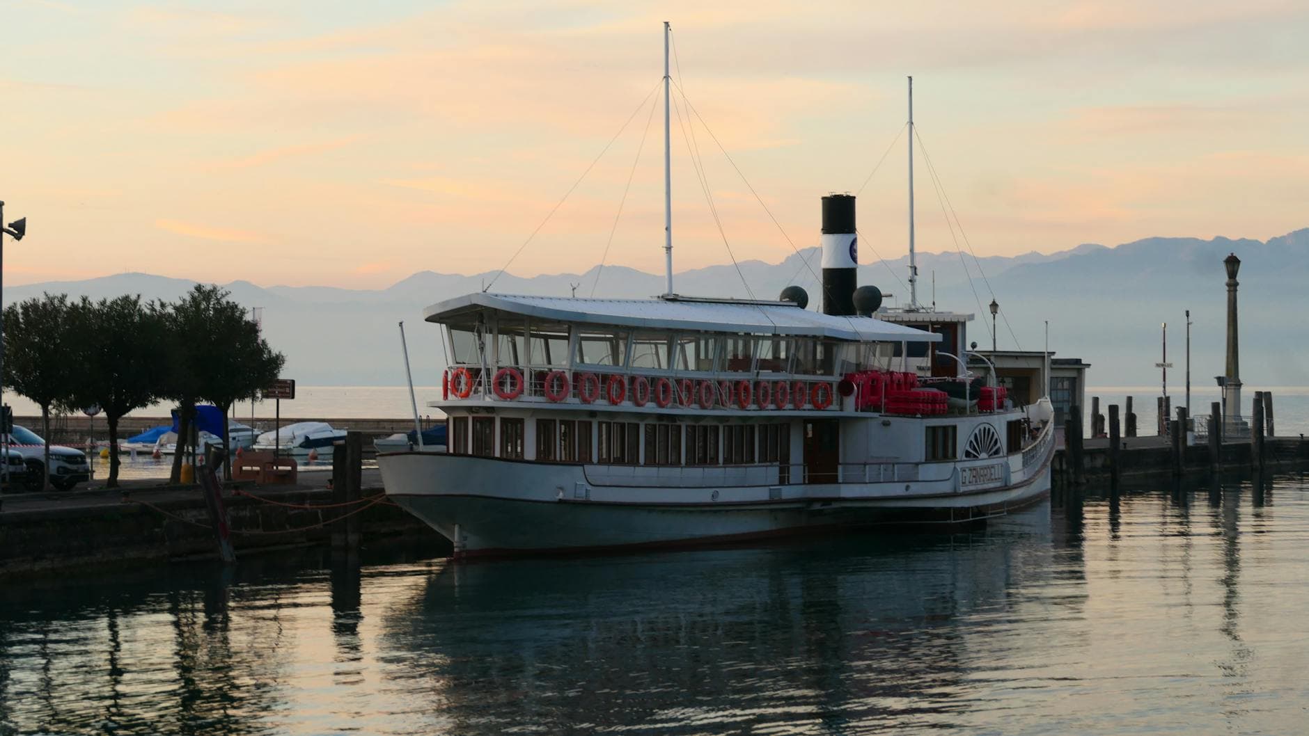 A tranquil sunset view of a boat docked at Peschiera del Garda, Italy.