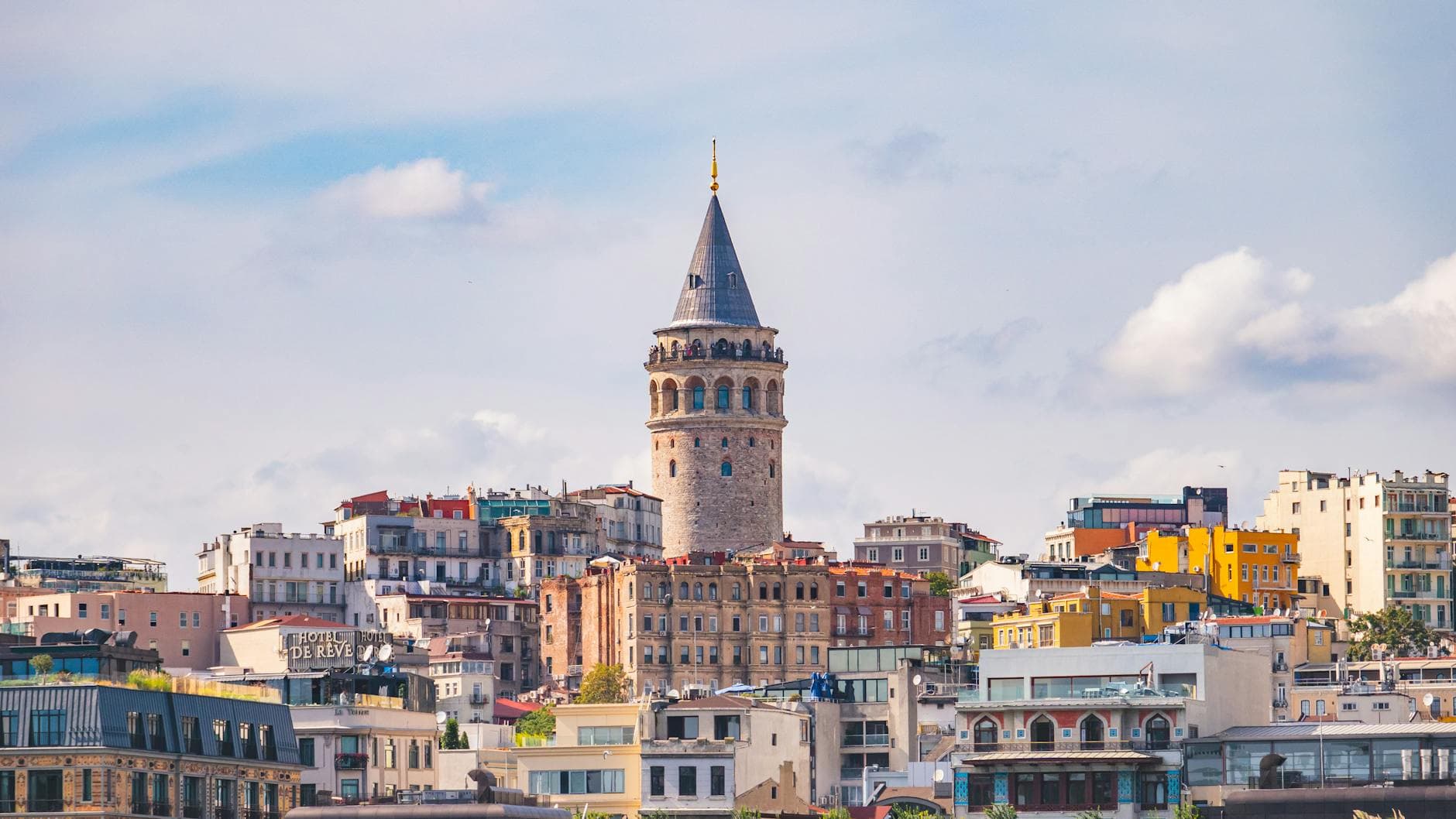 Colorful cityscape of Istanbul with Galata Tower under a bright blue sky.