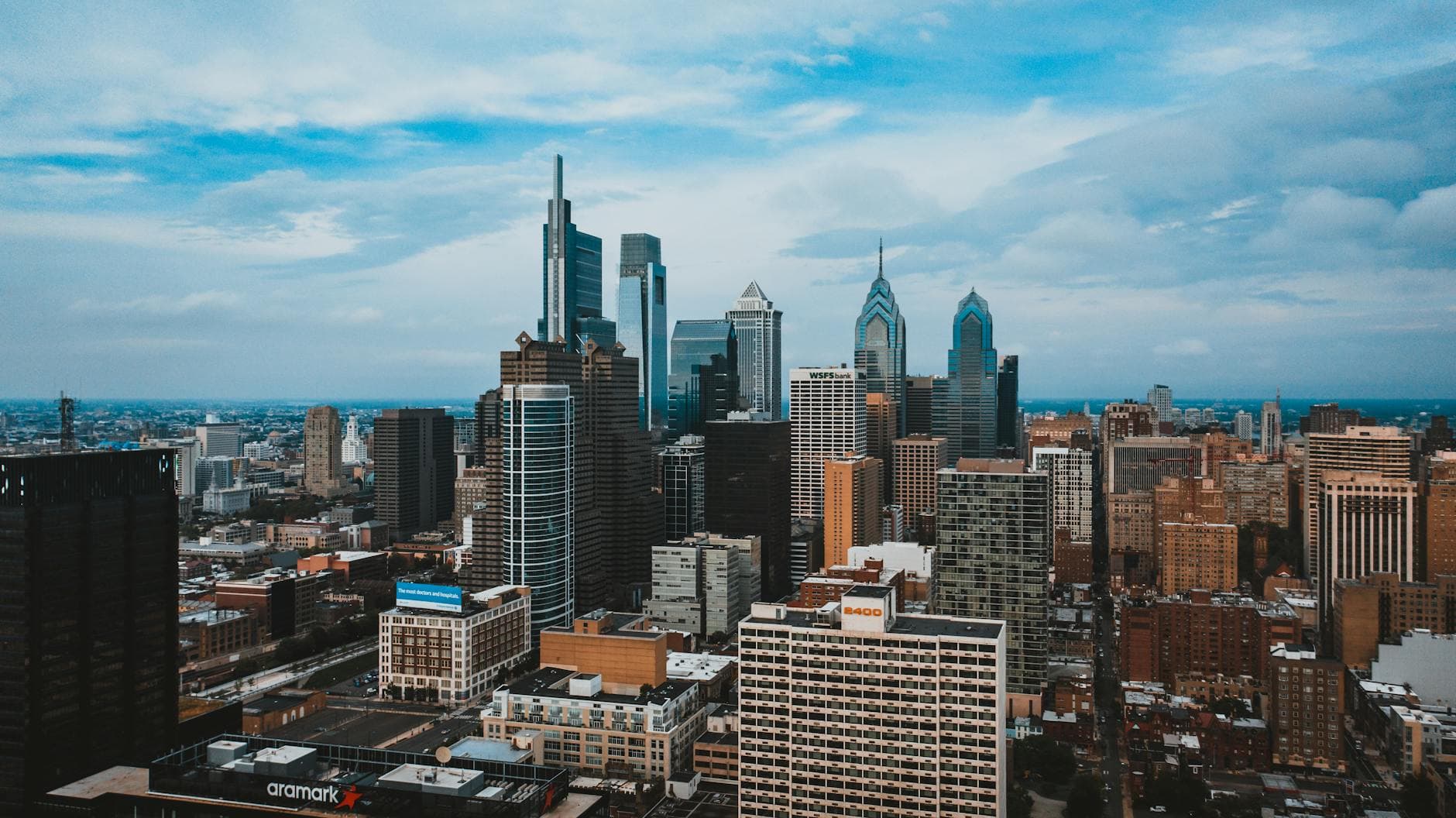 A stunning aerial view of Philadelphia's modern skyline with iconic skyscrapers under a blue sky.