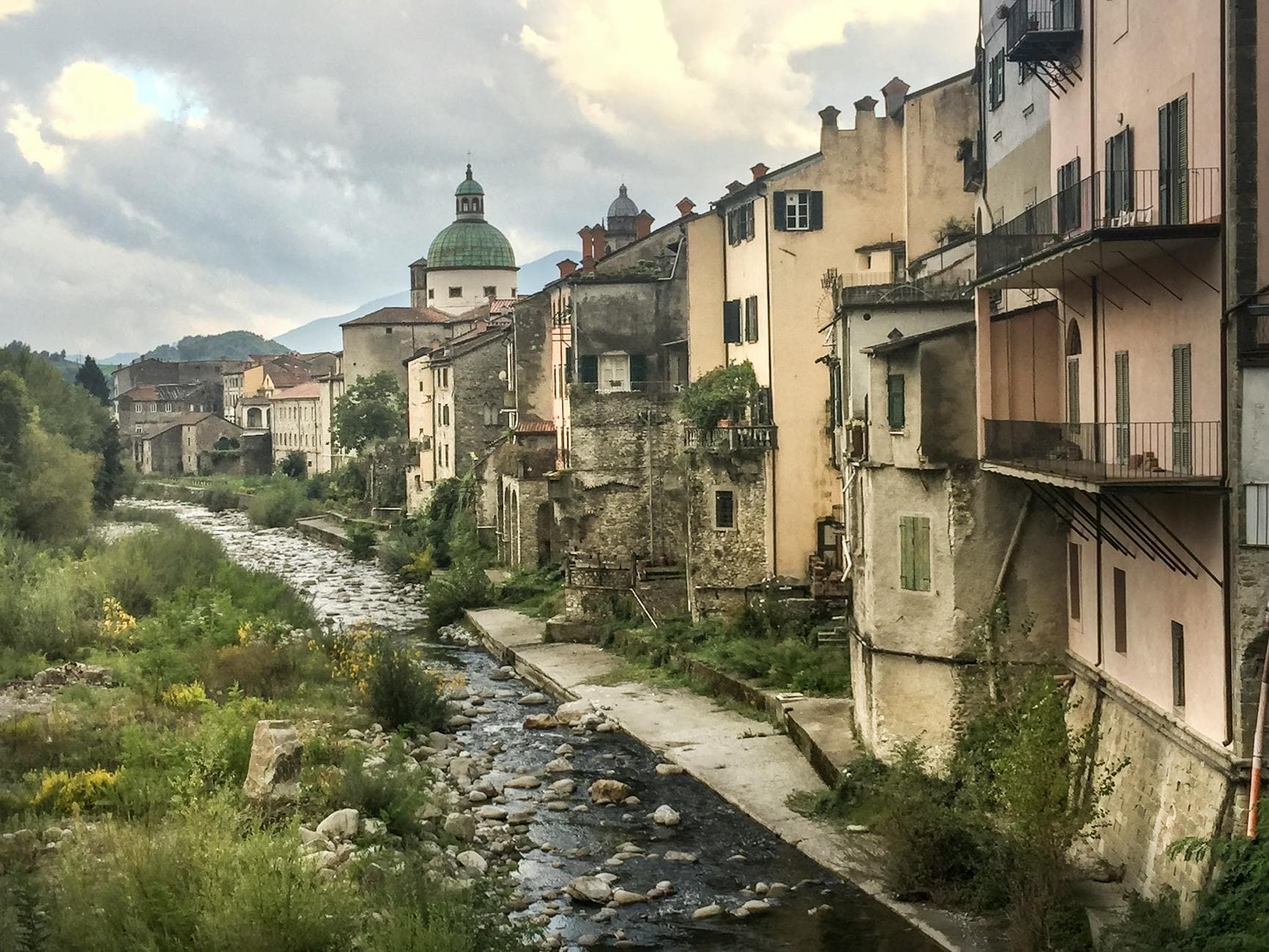 Scenic view of historic facades along a serene stream in Piacenza, Italy.