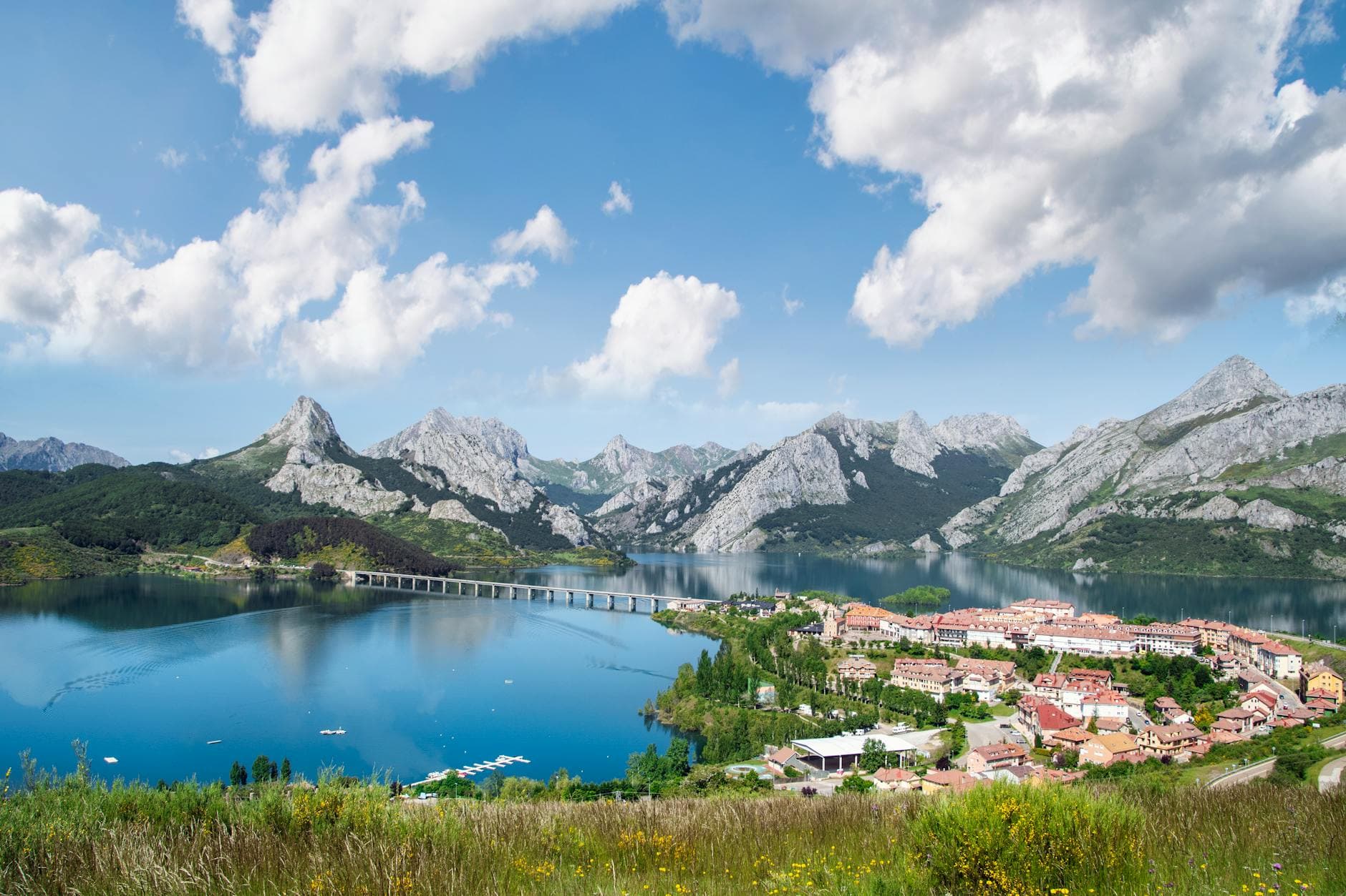 Picturesque landscape of Riaño village, lake, and mountains under a vibrant sky in Castilla y León, Spain.