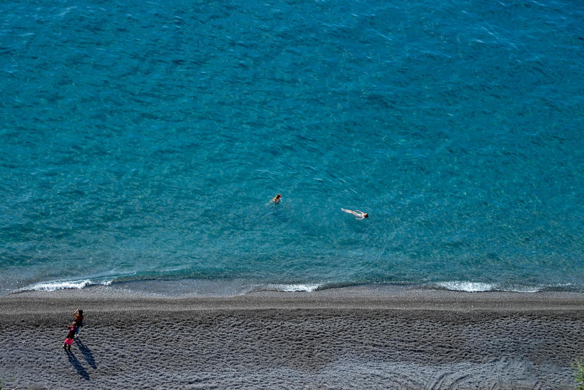 A stunning aerial shot capturing the beach and swimmers in crystal clear waters at the Amalfi Coast, Italy.