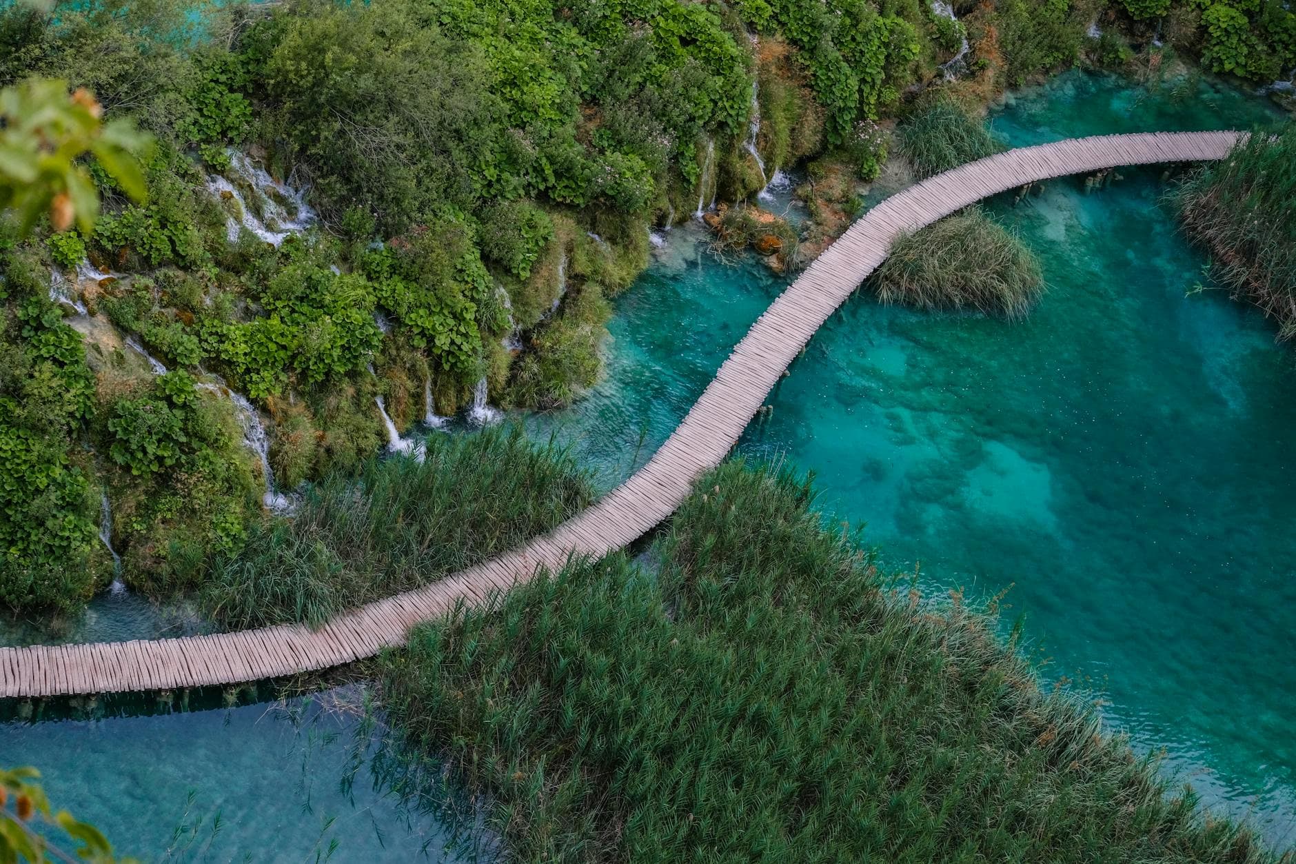 Aerial perspective of a wooden walkway over turquoise waters in Plitvice Lakes, Croatia.