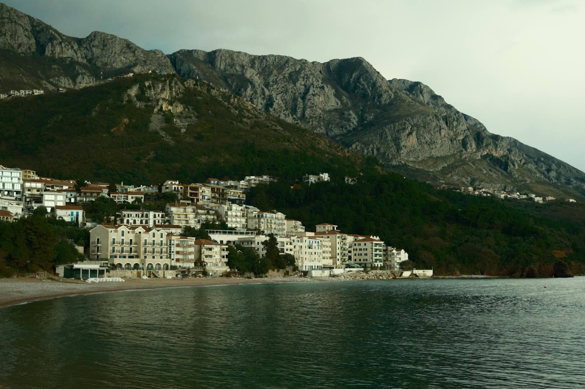 Picturesque coastal village with mountains in the background and serene waterfront.