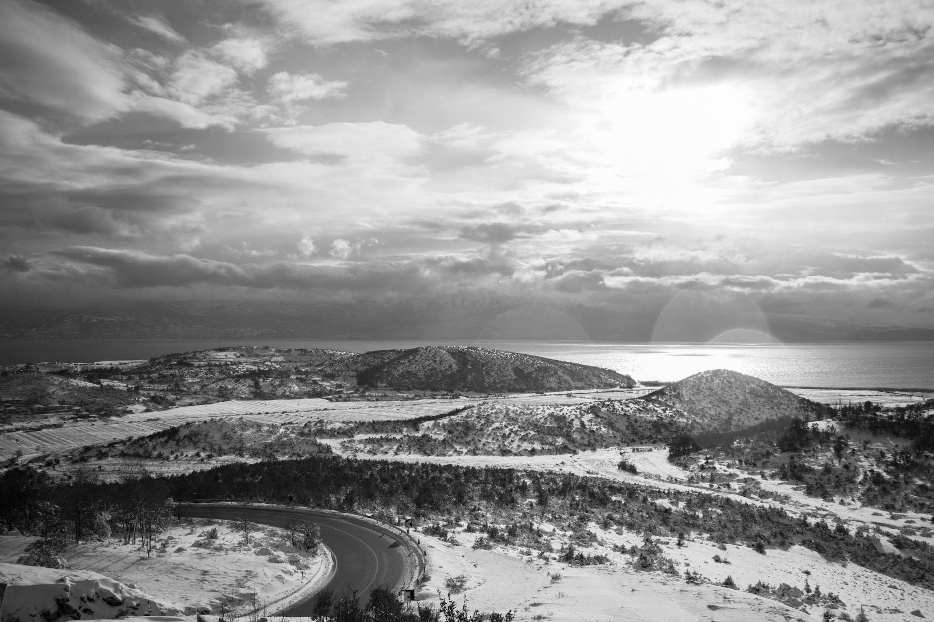 Breathtaking aerial view of a snowy winter landscape in Pogradec, Albania with hills and coastline.