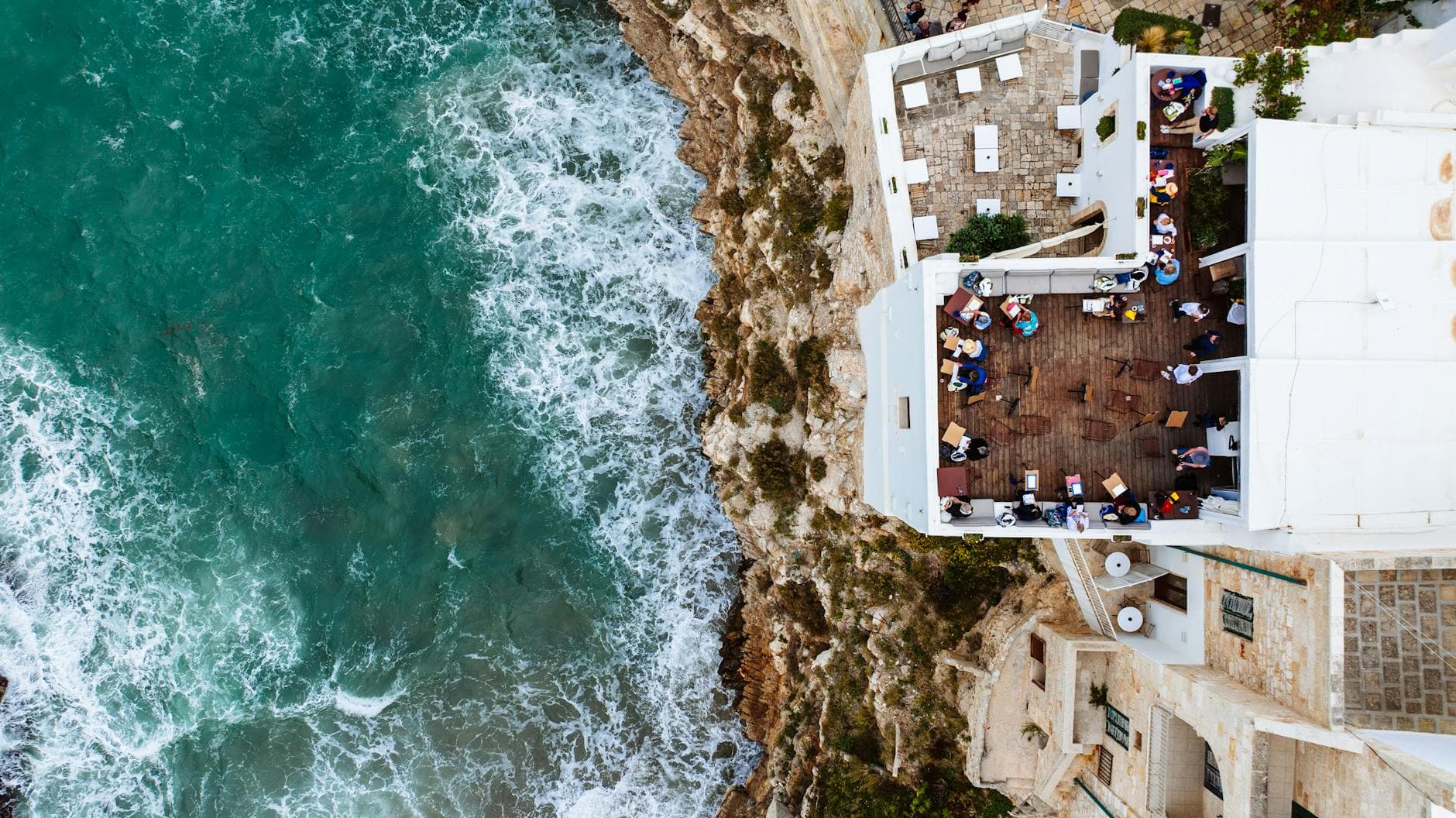 Captivating aerial view of a seaside dining terrace in Polignano a Mare, Puglia, Italy.