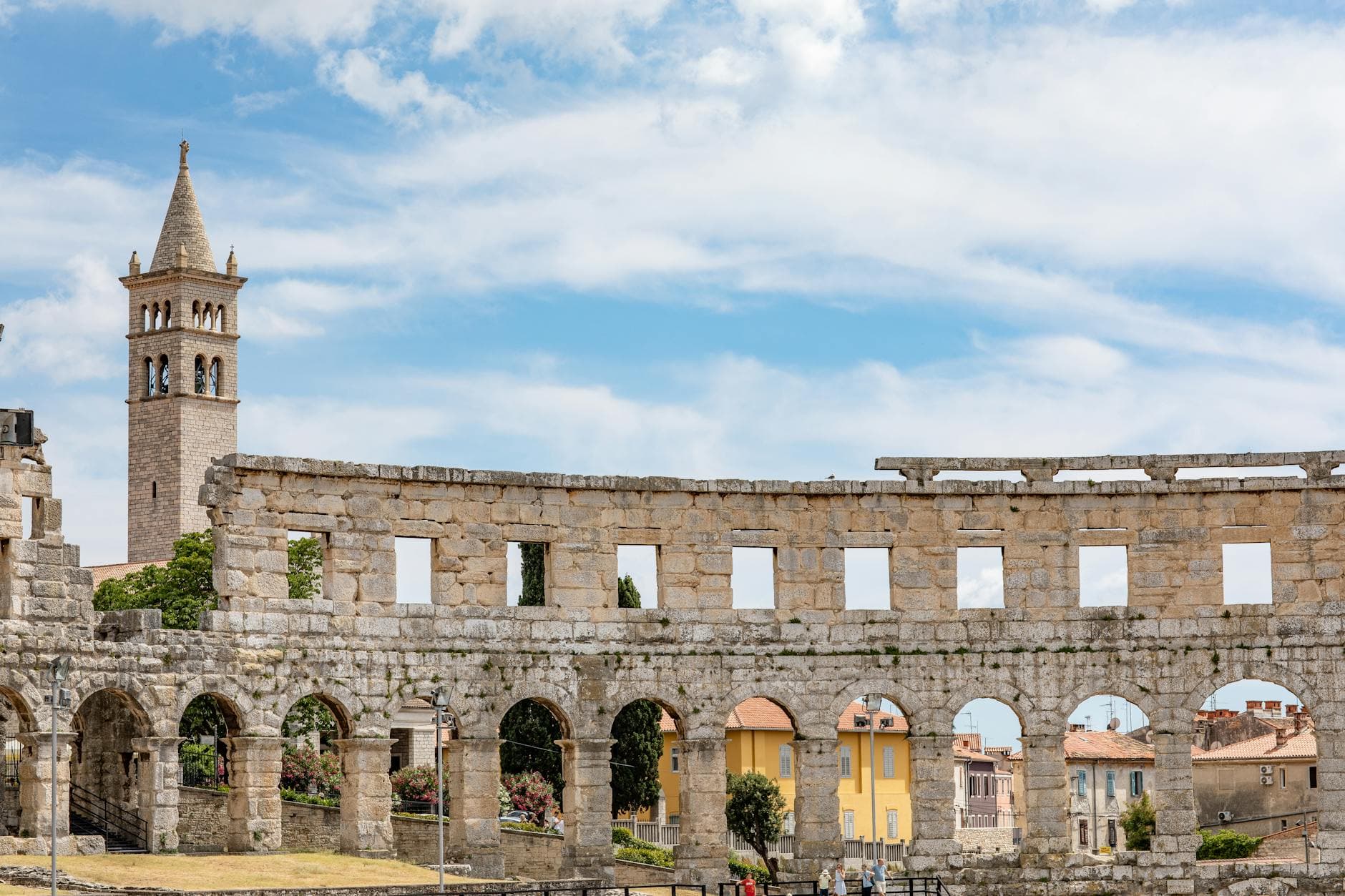Historic Pula Arena with bell tower in Croatia on a sunny day.