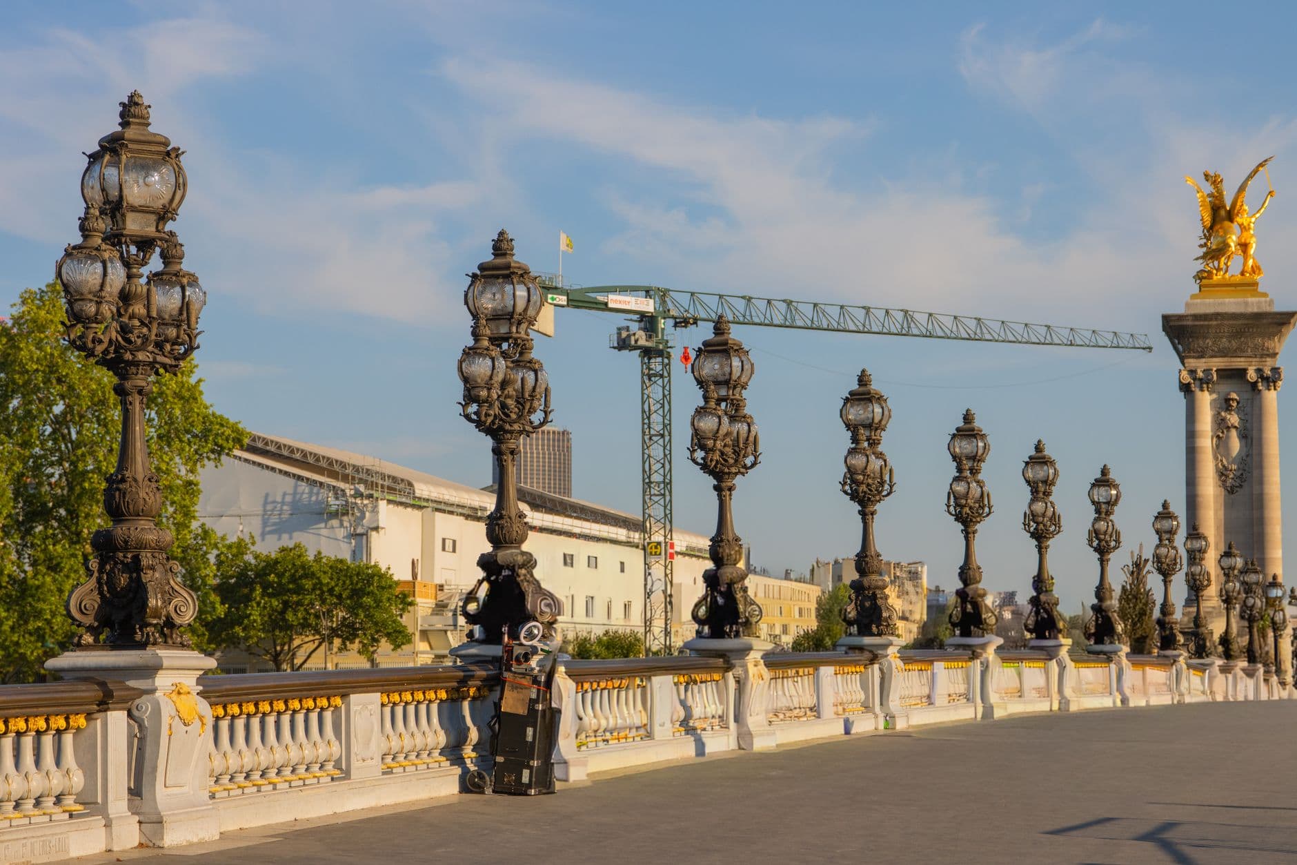 View of ornate lamp posts and architecture on Pont Alexandre III in Paris, showcasing historical charm.