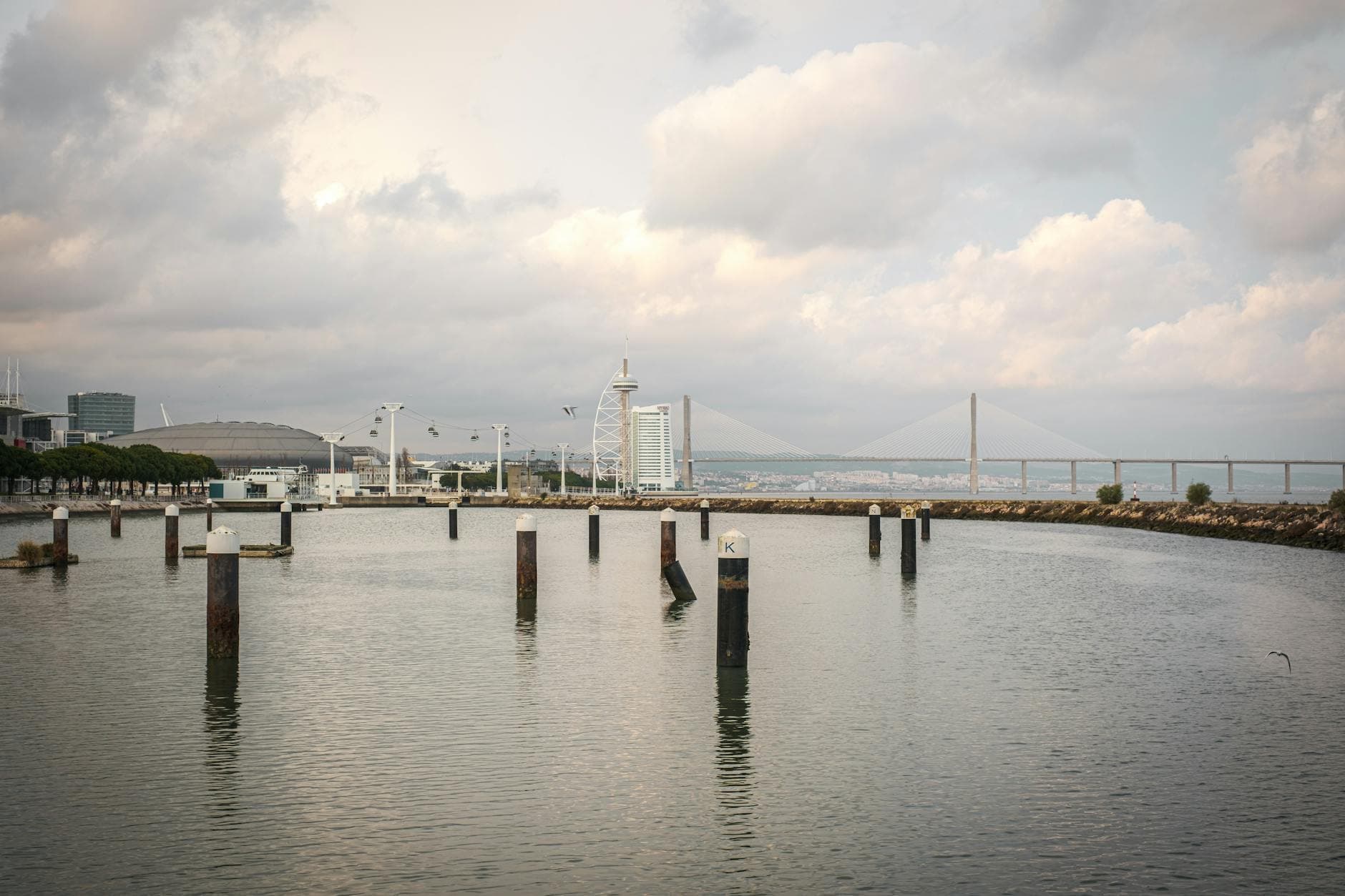 Beautiful view of Lisbon waterfront showcasing the Vasco da Gama Bridge under a cloudy sky.