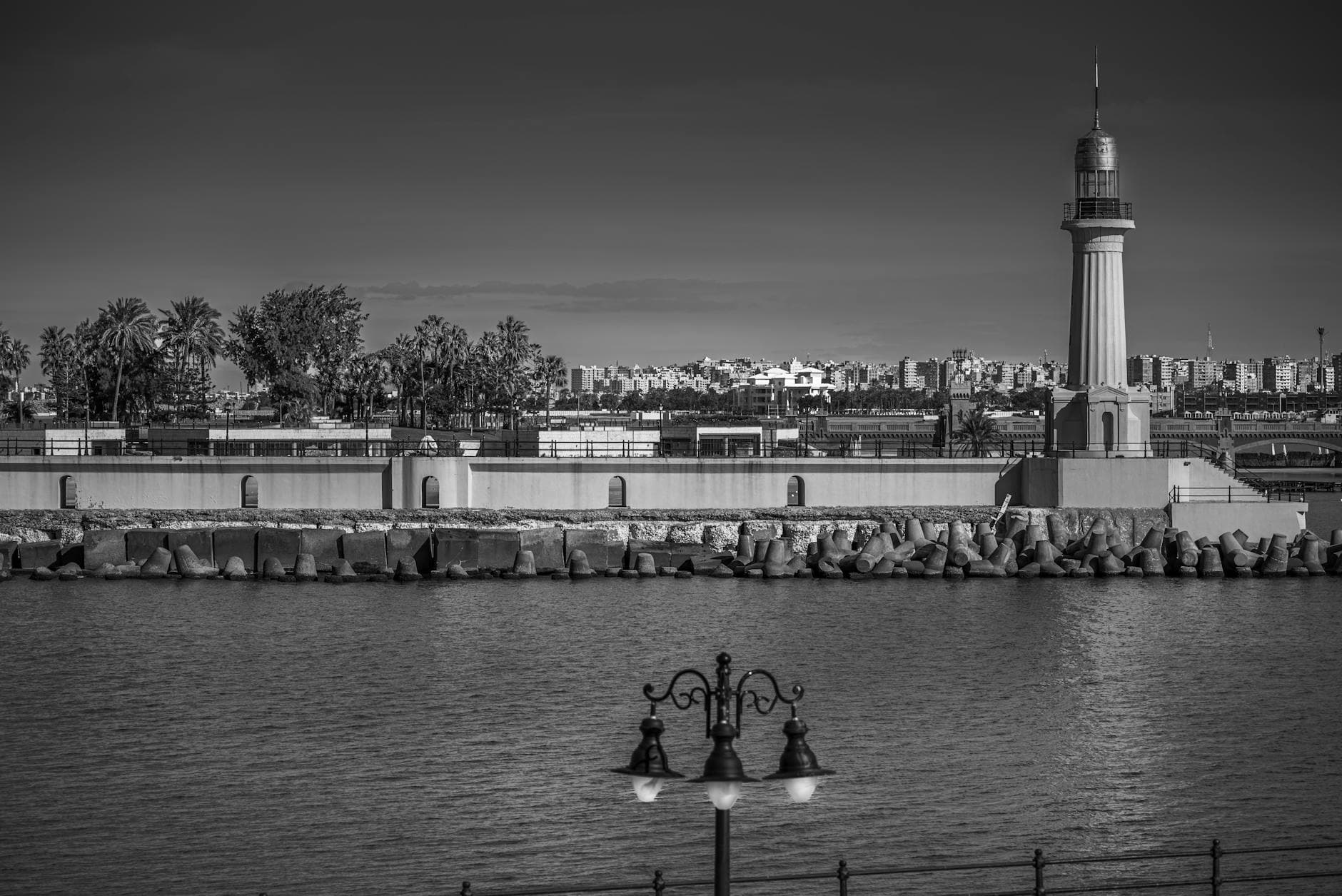Black and white view of a lighthouse and coastal scenery in Alexandria, Egypt.