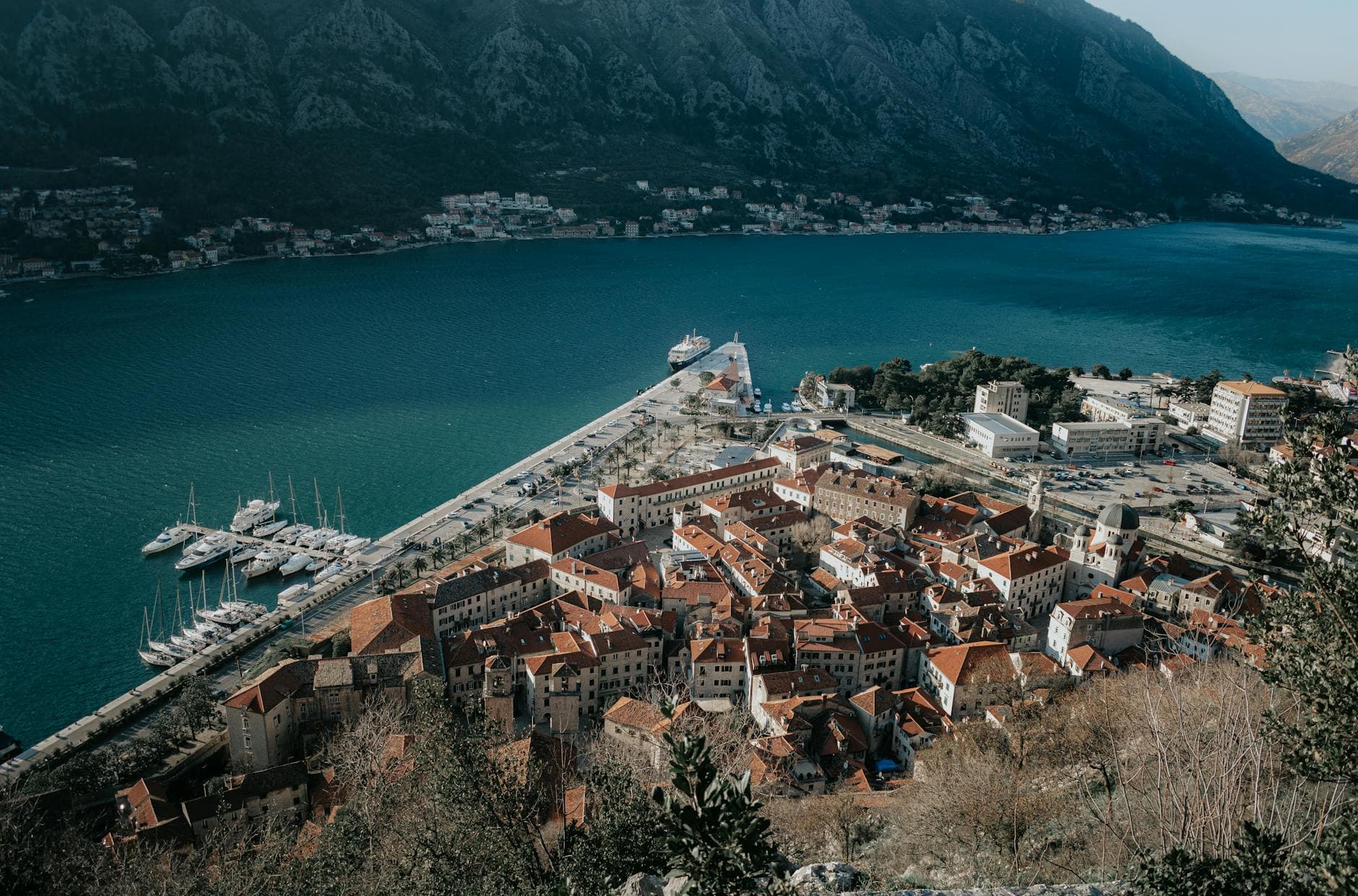 Breathtaking aerial view of Kotor's coastal town, marina, and mountains in Montenegro.