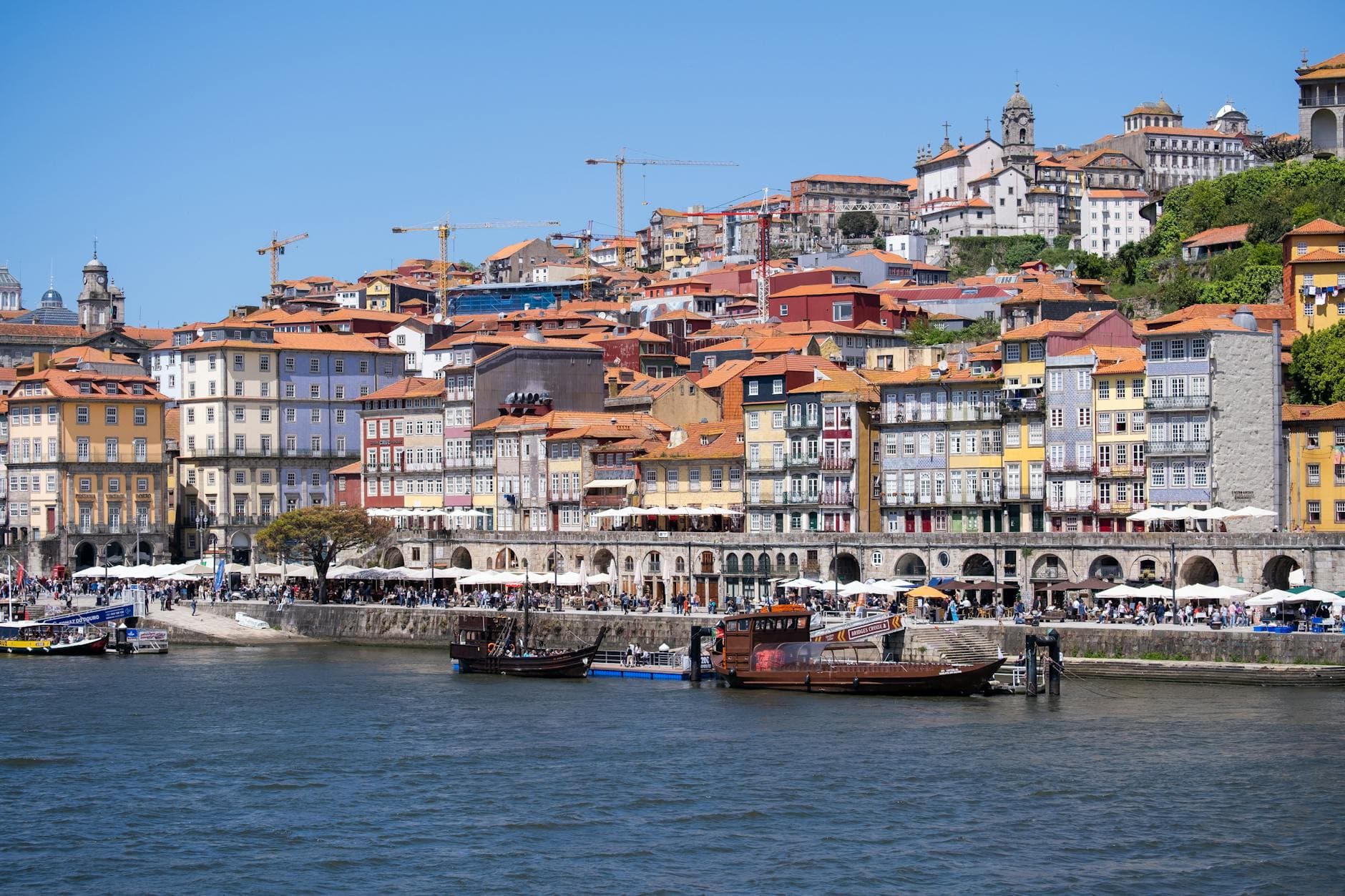Colorful waterfront view of Ribeira District, Porto's historic charm under a bright sky.
