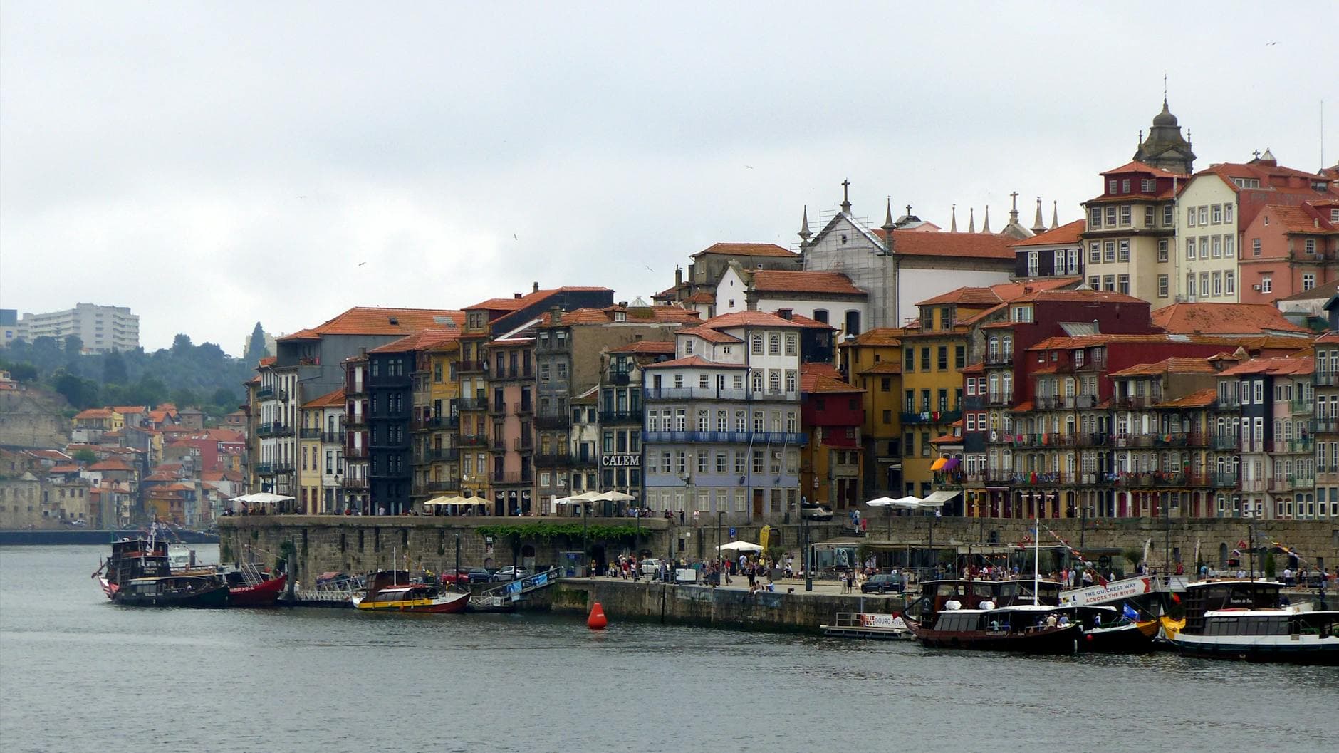 Vibrant cityscape of Porto's waterfront with historic architecture and boats along the Douro River.