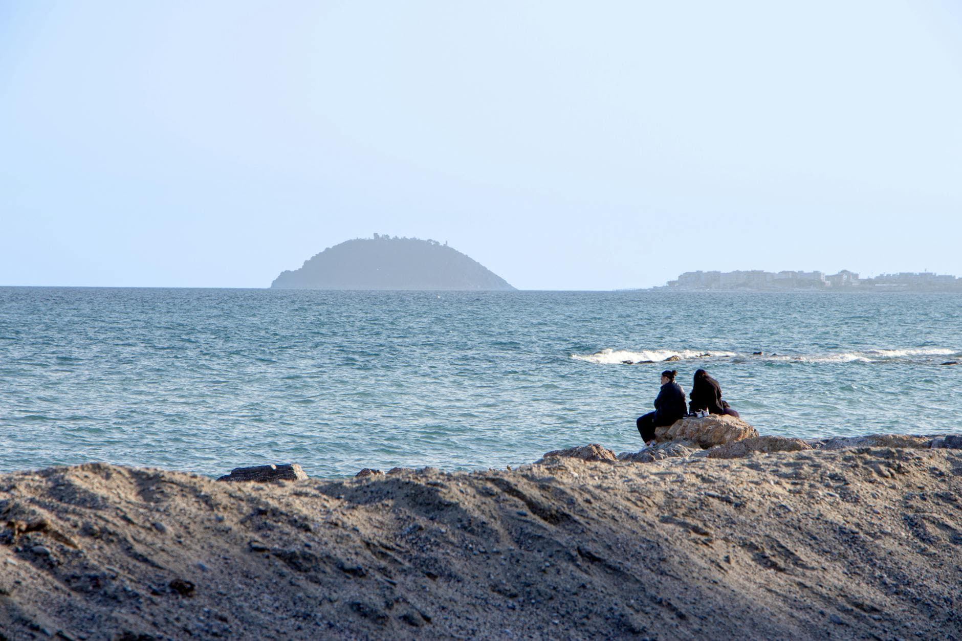 Two people enjoying a peaceful moment by the beach in Borghetto Santo Spirito, Liguria, Italy.