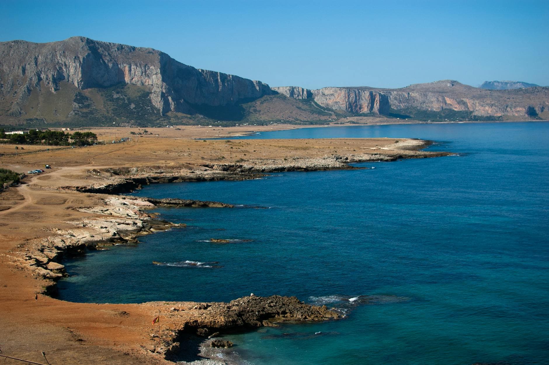 Breathtaking view of Gulf of Macari's rocky coastline in Sicily, Italy, with clear blue skies.