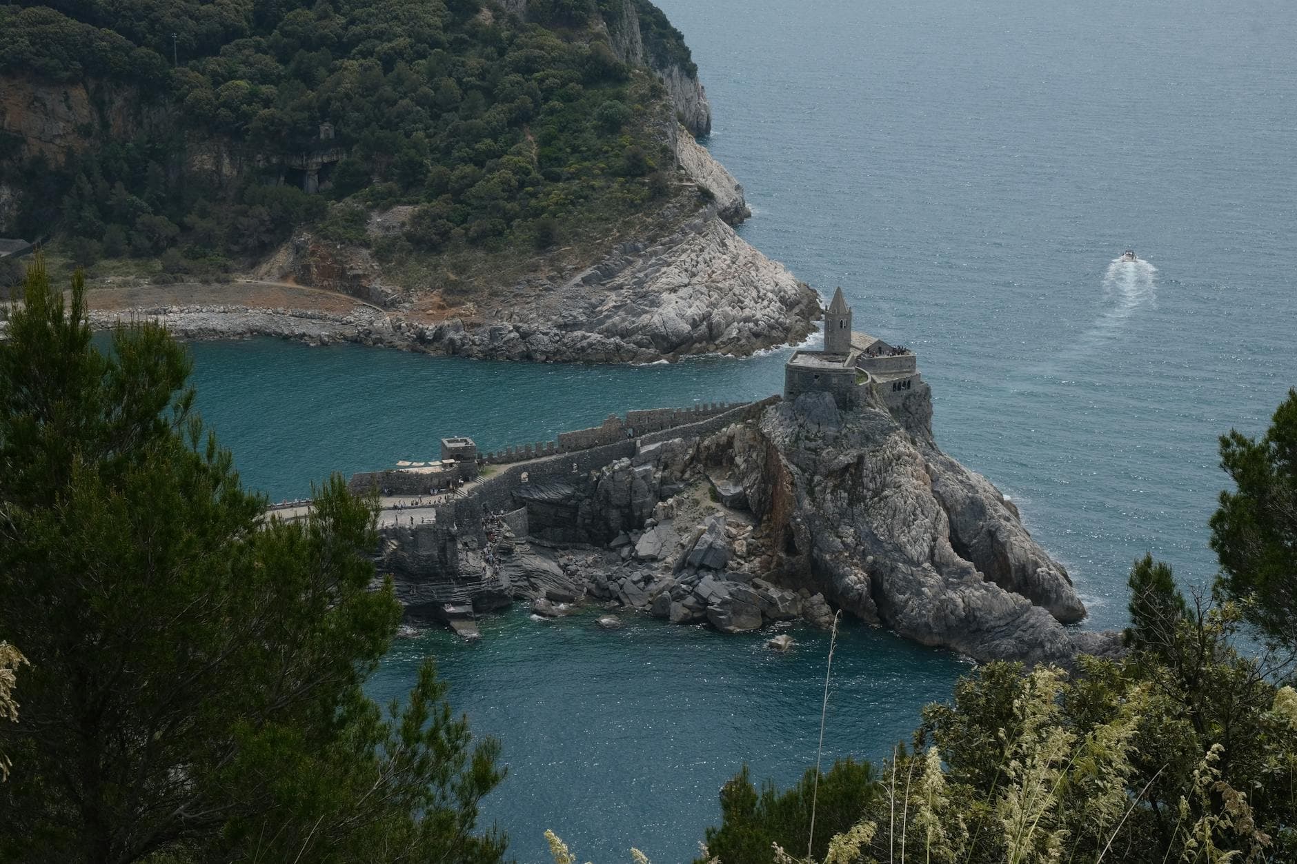 Aerial view of Porto Venere's iconic coastal church surrounded by turquoise waters and lush cliffs.