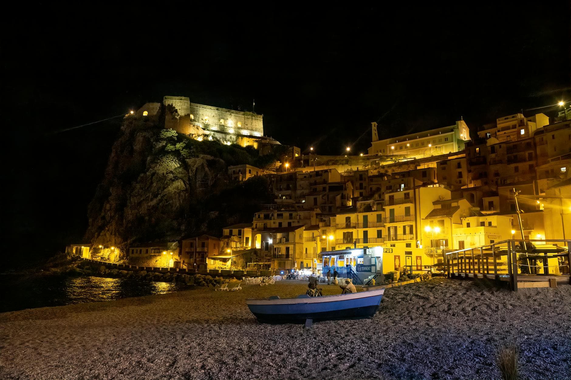 Stunning night view of Scilla's illuminated beachside with historic fort.