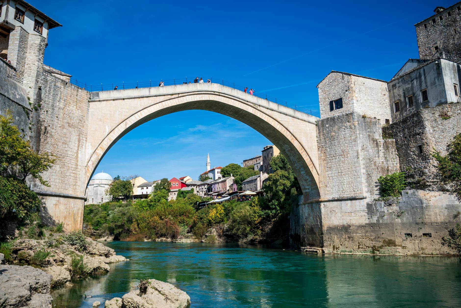 View of the historic Stari Most bridge in Mostar, Bosnia, under a clear blue sky.