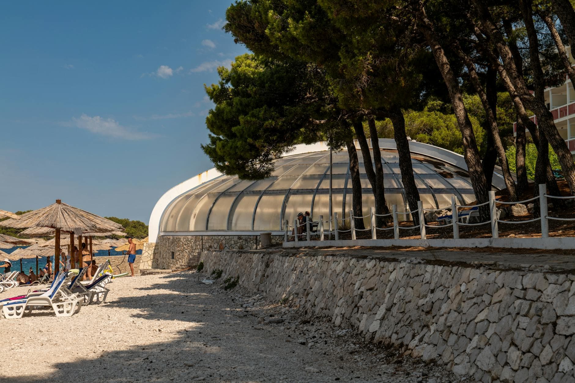 A beach view featuring a dome structure and lounge chairs in Primošten, Croatia.