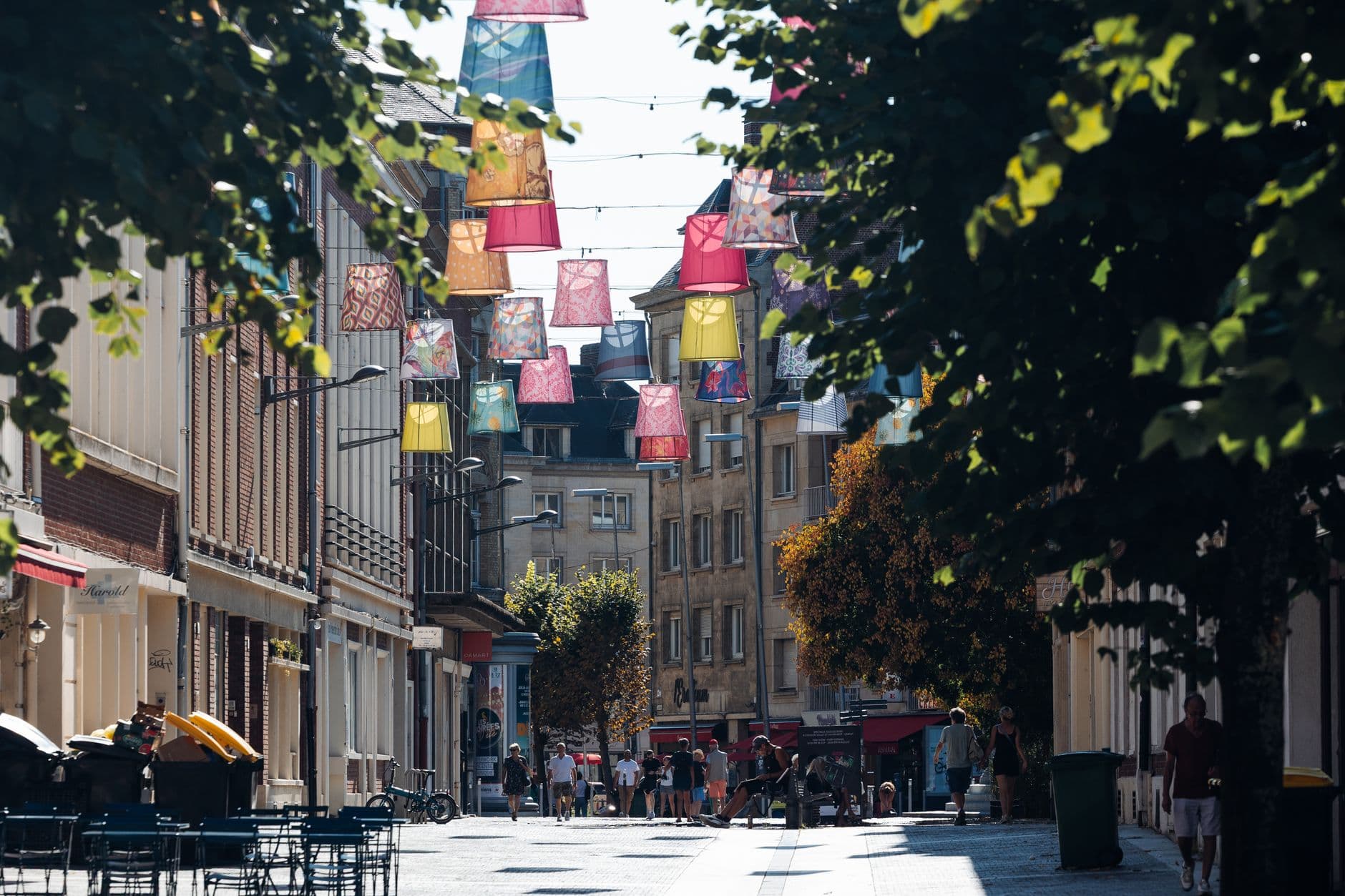 Colorful street scene with hanging lanterns in Amiens, showcasing European architecture.