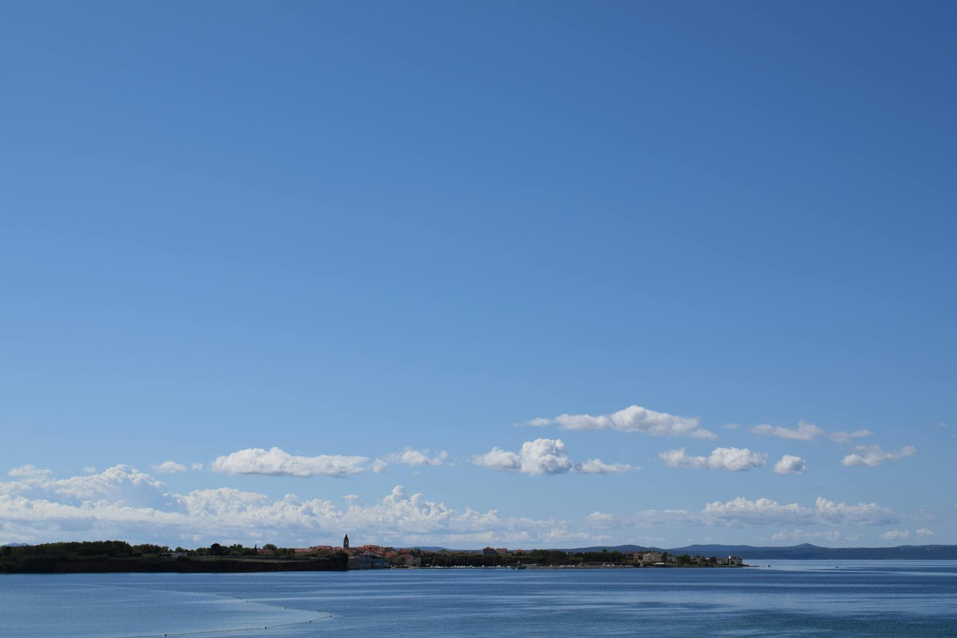 A serene view of the coastline in Privlaka, Croatia under a clear blue sky.