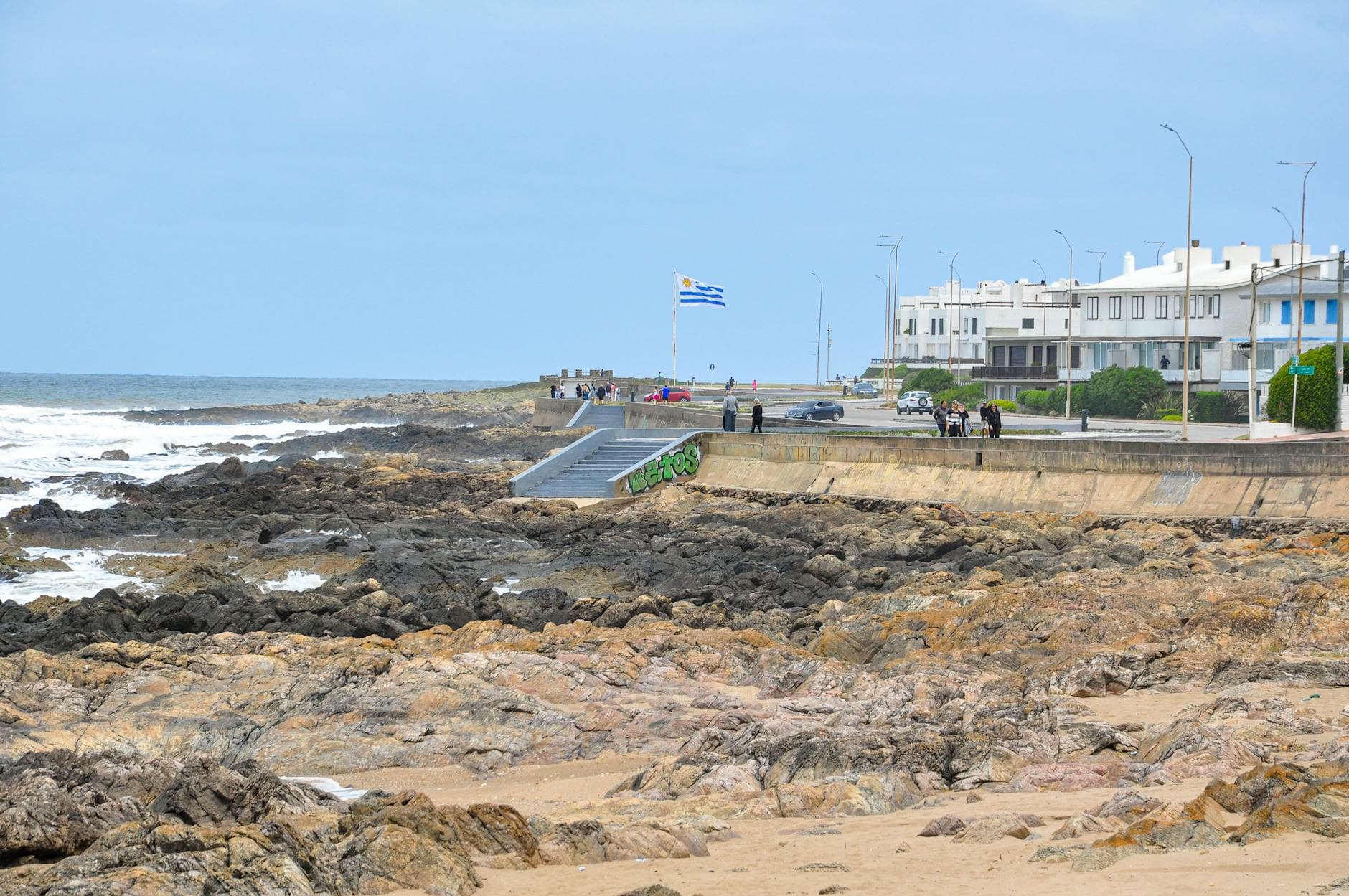 Coastal scene with rocky shore and cityscape in Punta del Este, Uruguay.