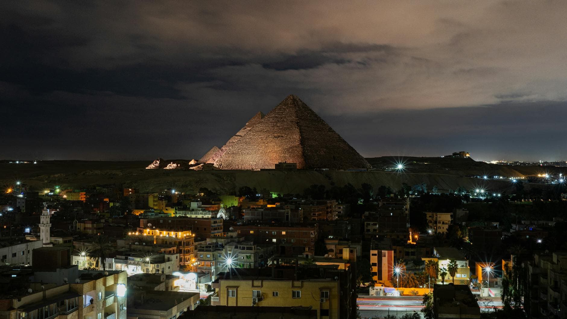 A stunning night view of the Giza Pyramids illuminated, capturing the vibrant cityscape of Giza, Egypt.