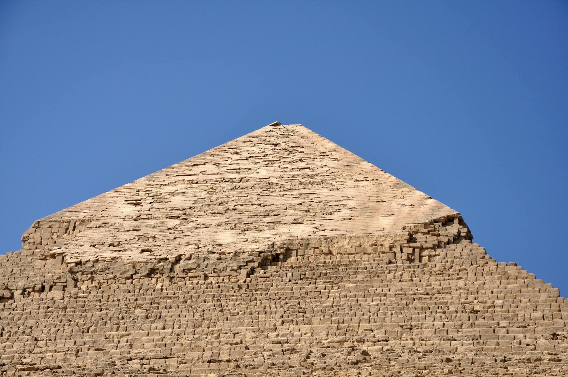 Close-up of an ancient Egyptian pyramid against a clear blue sky, showcasing its monumental architecture.