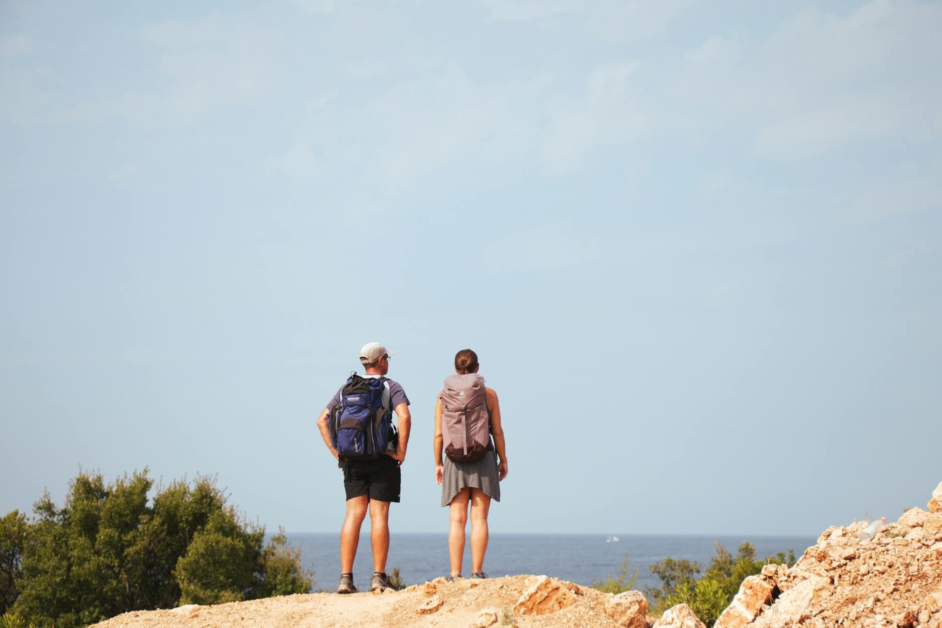 A couple stands on a cliff in Vlorë, Albania, enjoying a breathtaking coastal view.