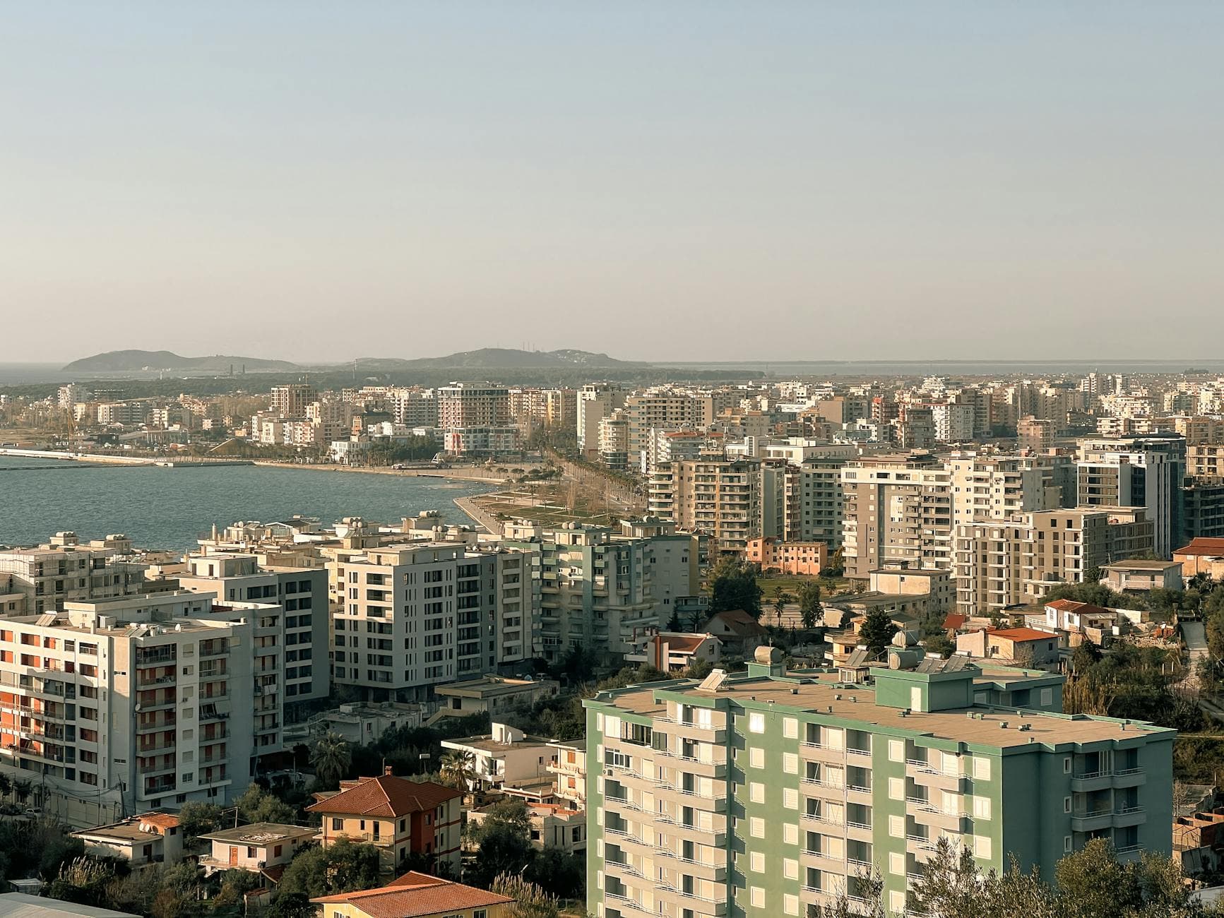 An aerial shot showcasing a coastal city with modern residential buildings and the sea in view.