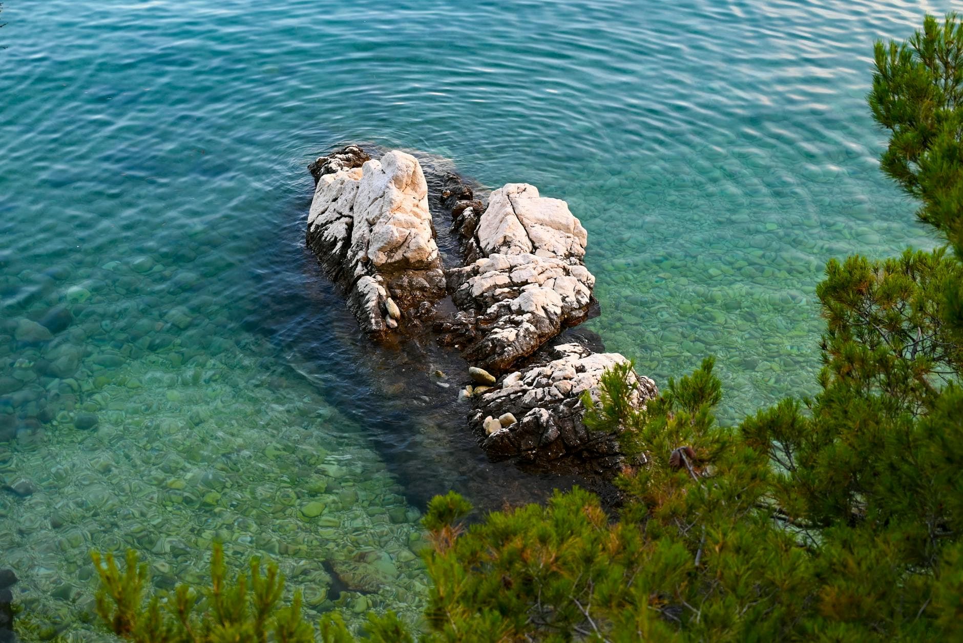 Aerial view of clear turquoise waters and rocky shoreline in Rabac, Croatia.