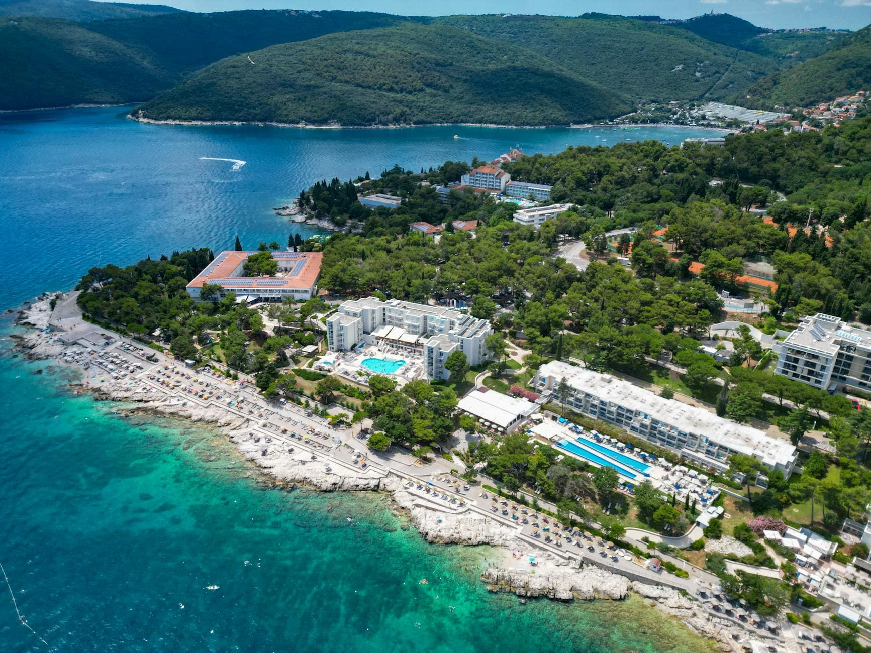 Stunning aerial view of Rabac's coastline with hotels, turquoise waters, and lush greenery in Istria, Croatia.