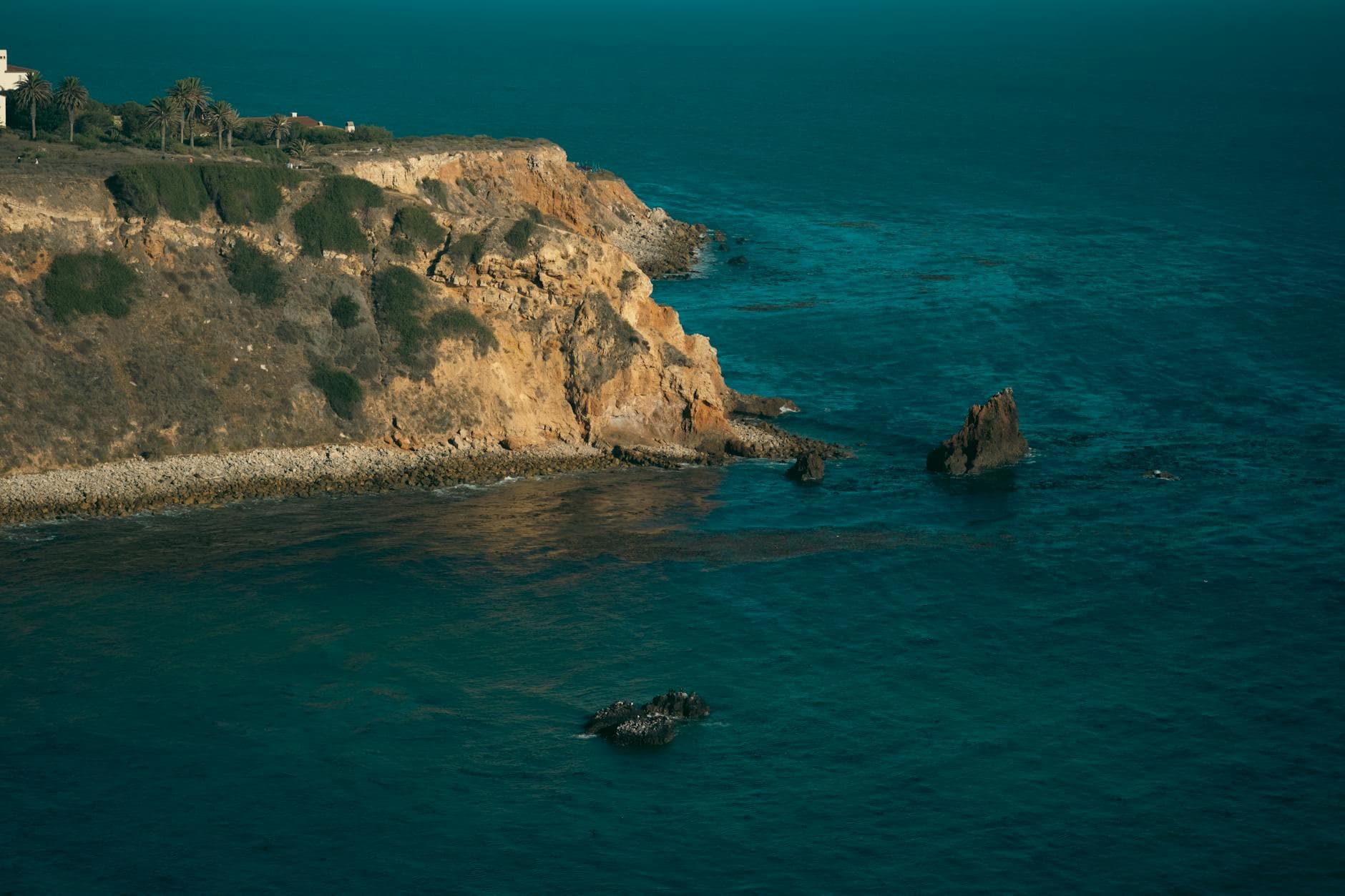 A striking coastal cliff overlooking the ocean, captured at sunset with waves crashing against rocks, evoking serenity and adventure.