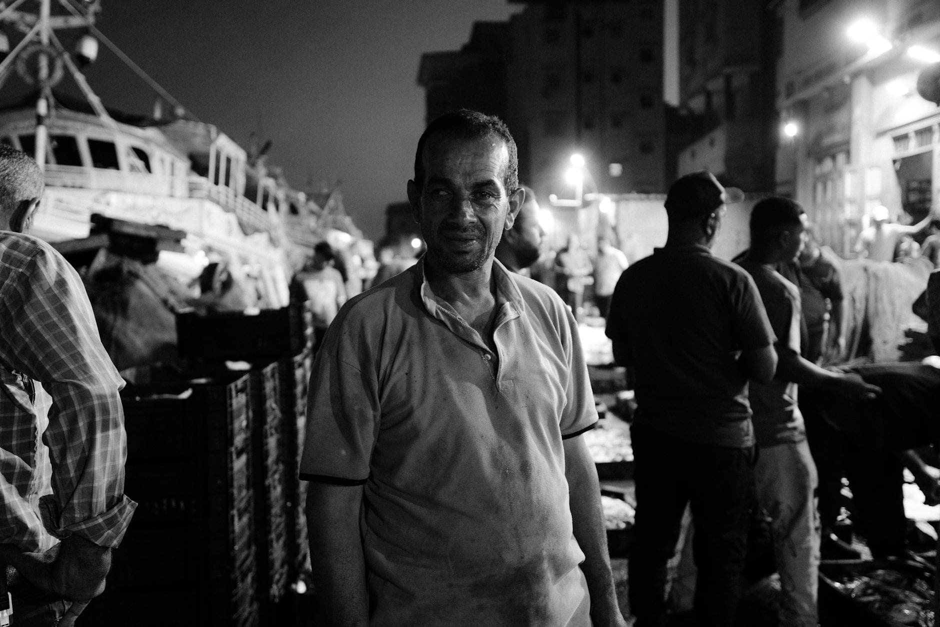 Nighttime street photo capturing local life in Ras El-Bar, Egypt with fishermen and boats.