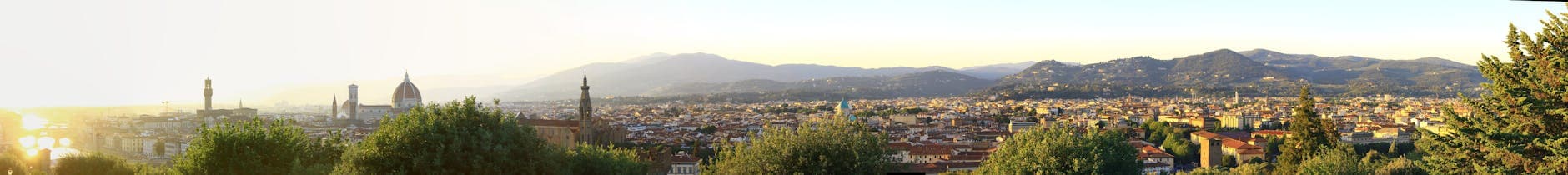 Panoramic view of the Florence skyline with the Cathedral and hills at sunset.