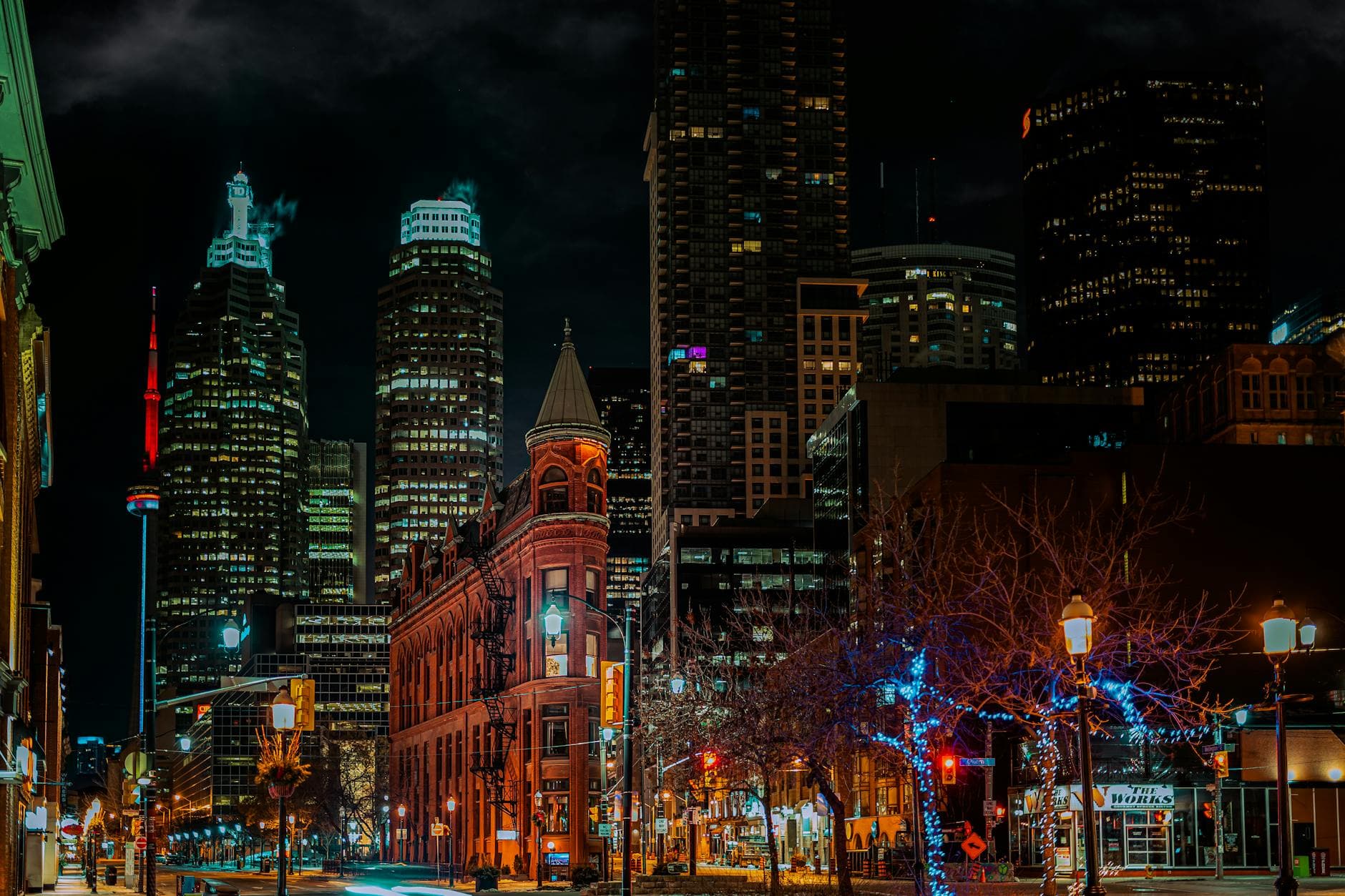 Vibrant night view of downtown Toronto skyline featuring the iconic CN Tower and historic buildings.