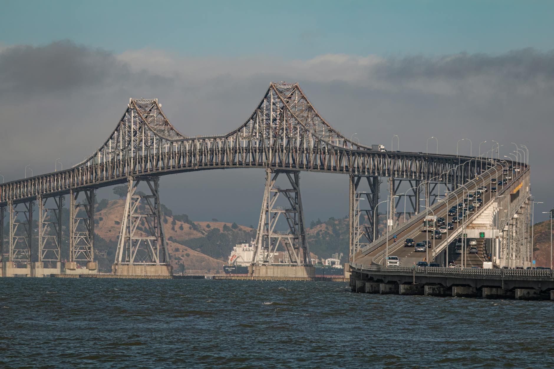 Dramatic view of the Richmond-San Rafael Bridge amidst fog and urban traffic over bay waters.