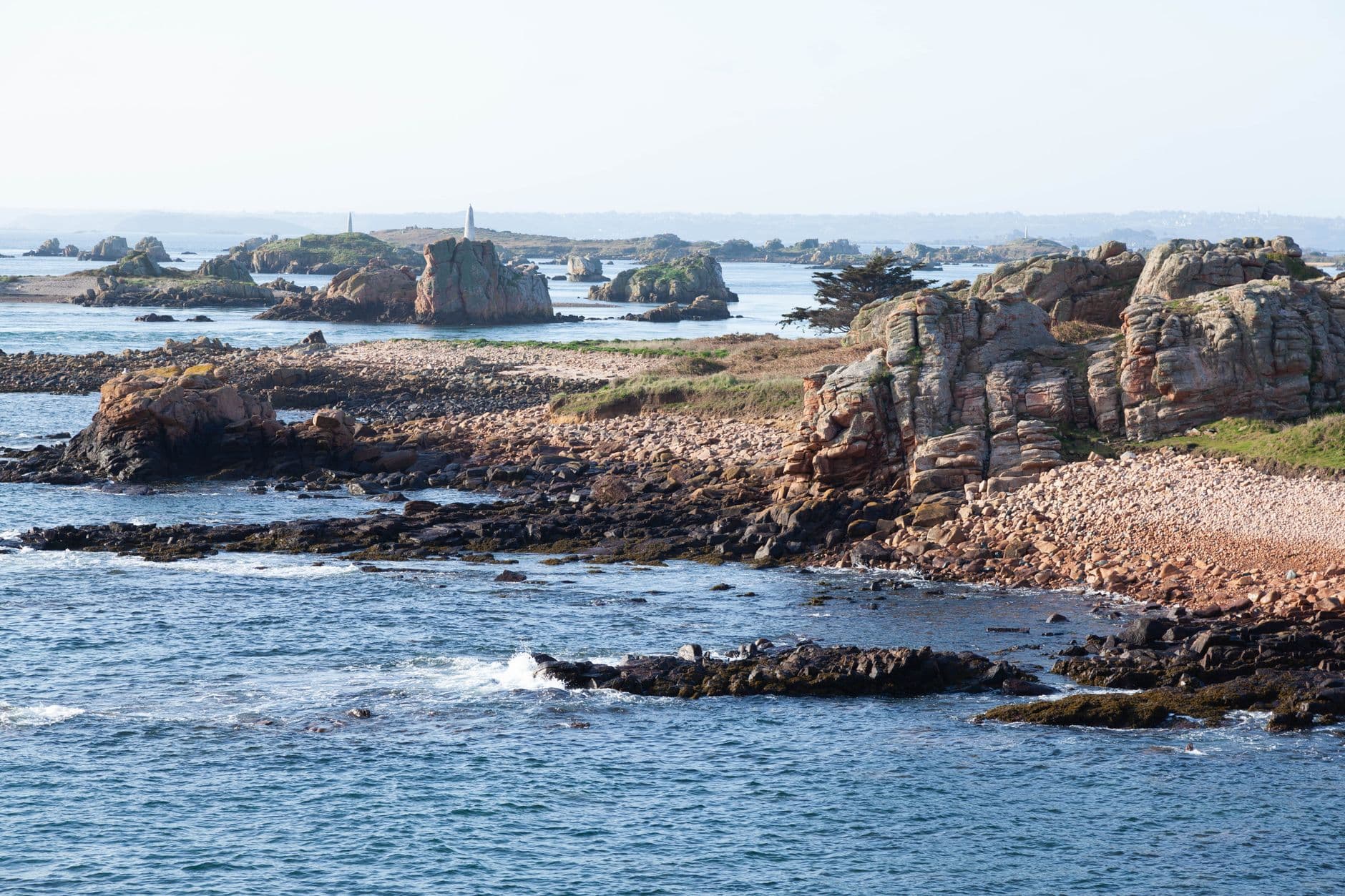 Aerial view of rocky coastline on Île-de-Bréhat in Brittany, France with lush landscape and clear waters.