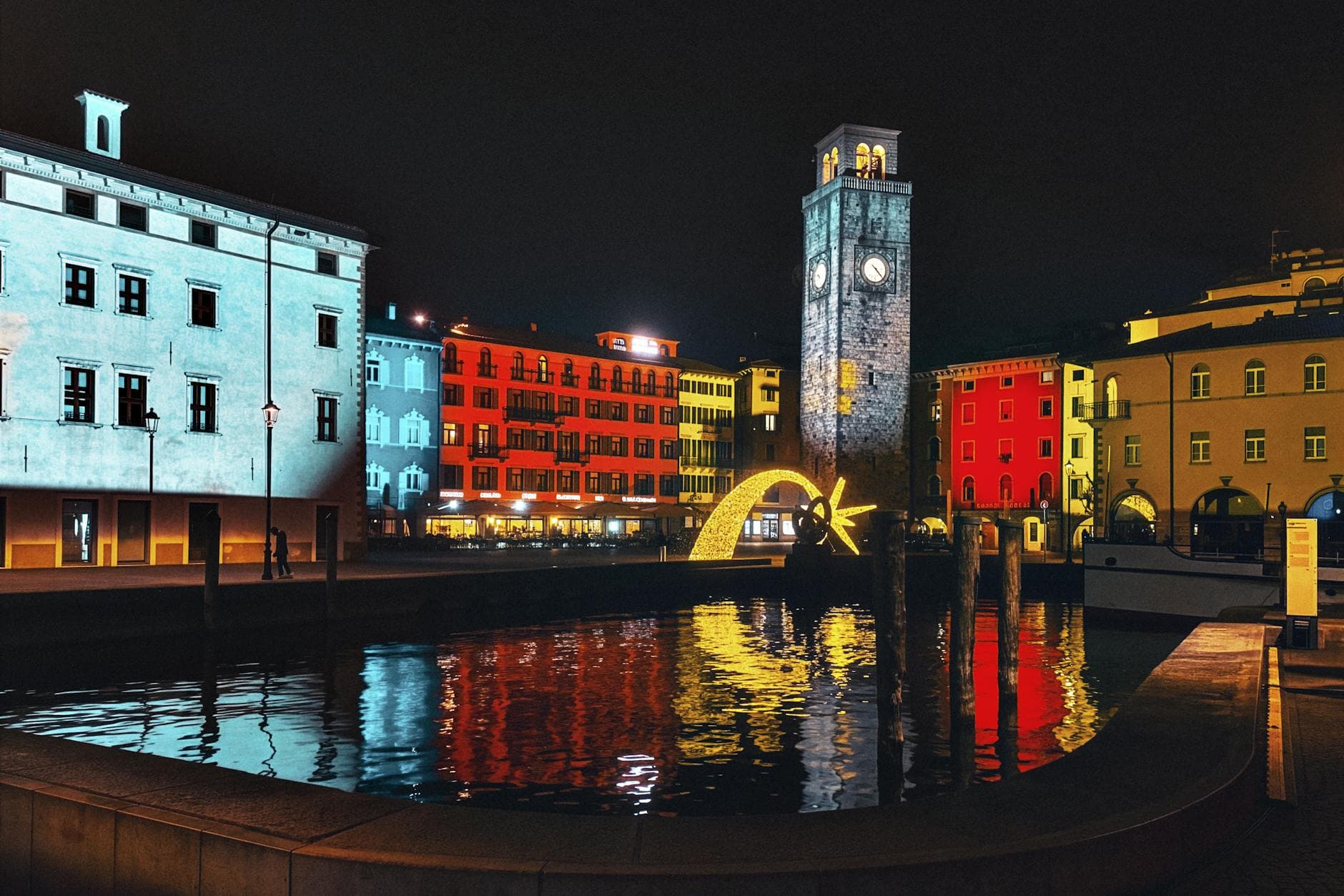 Colorful night view of the clock tower and waterfront in Riva del Garda, Italy.