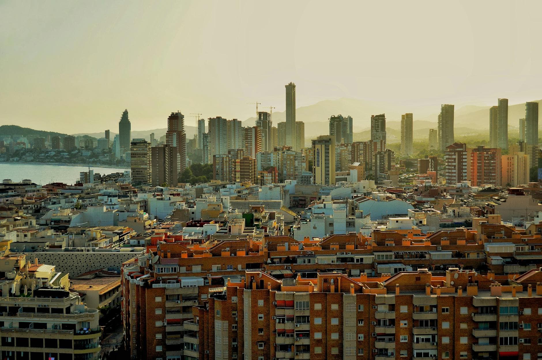 Stunning aerial view of Benidorm skyline with modern skyscrapers and coastal buildings at sunset.