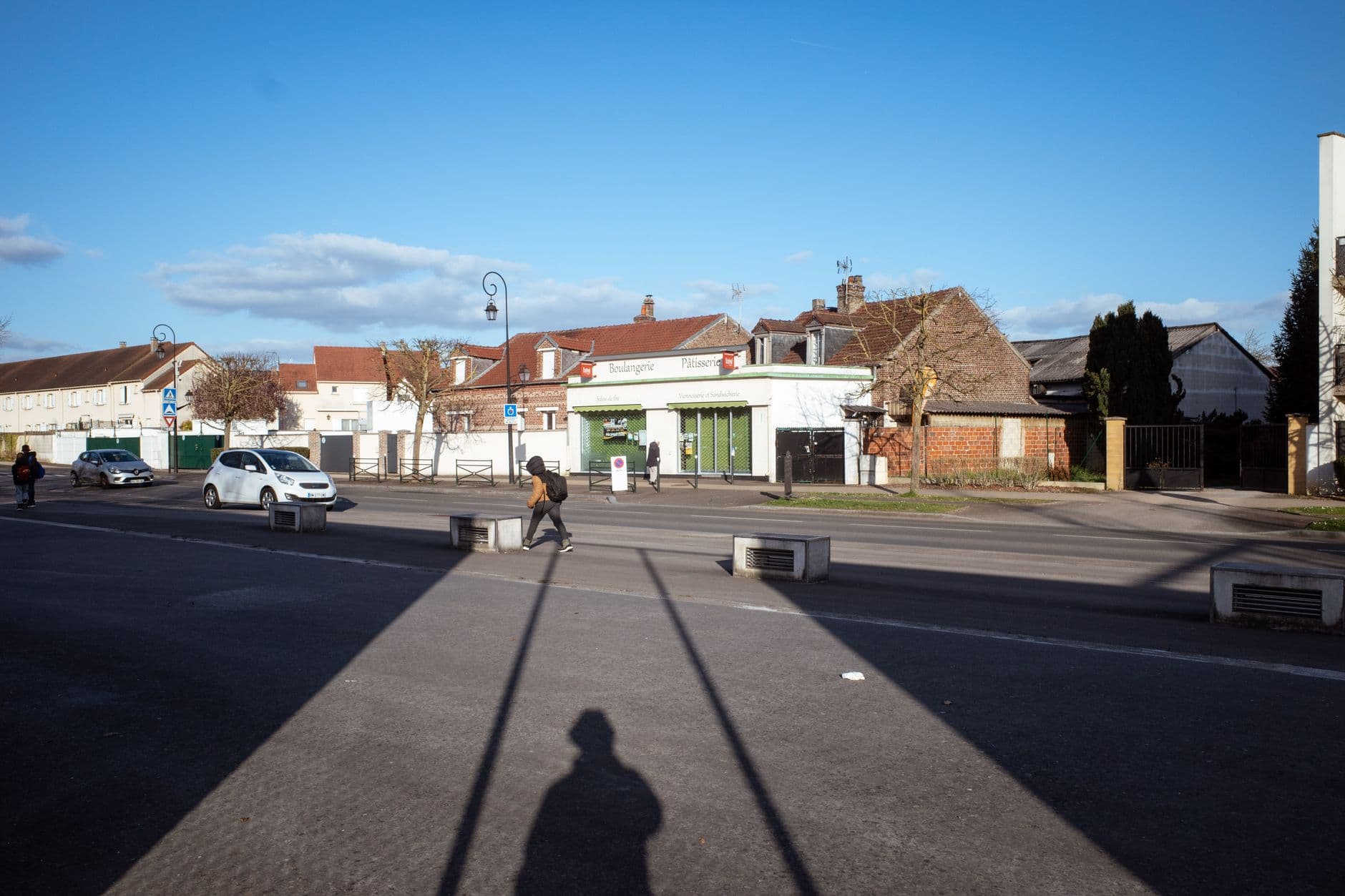 Tranquil suburban street scene in Compiègne, Hauts-de-France, France with people and cars.